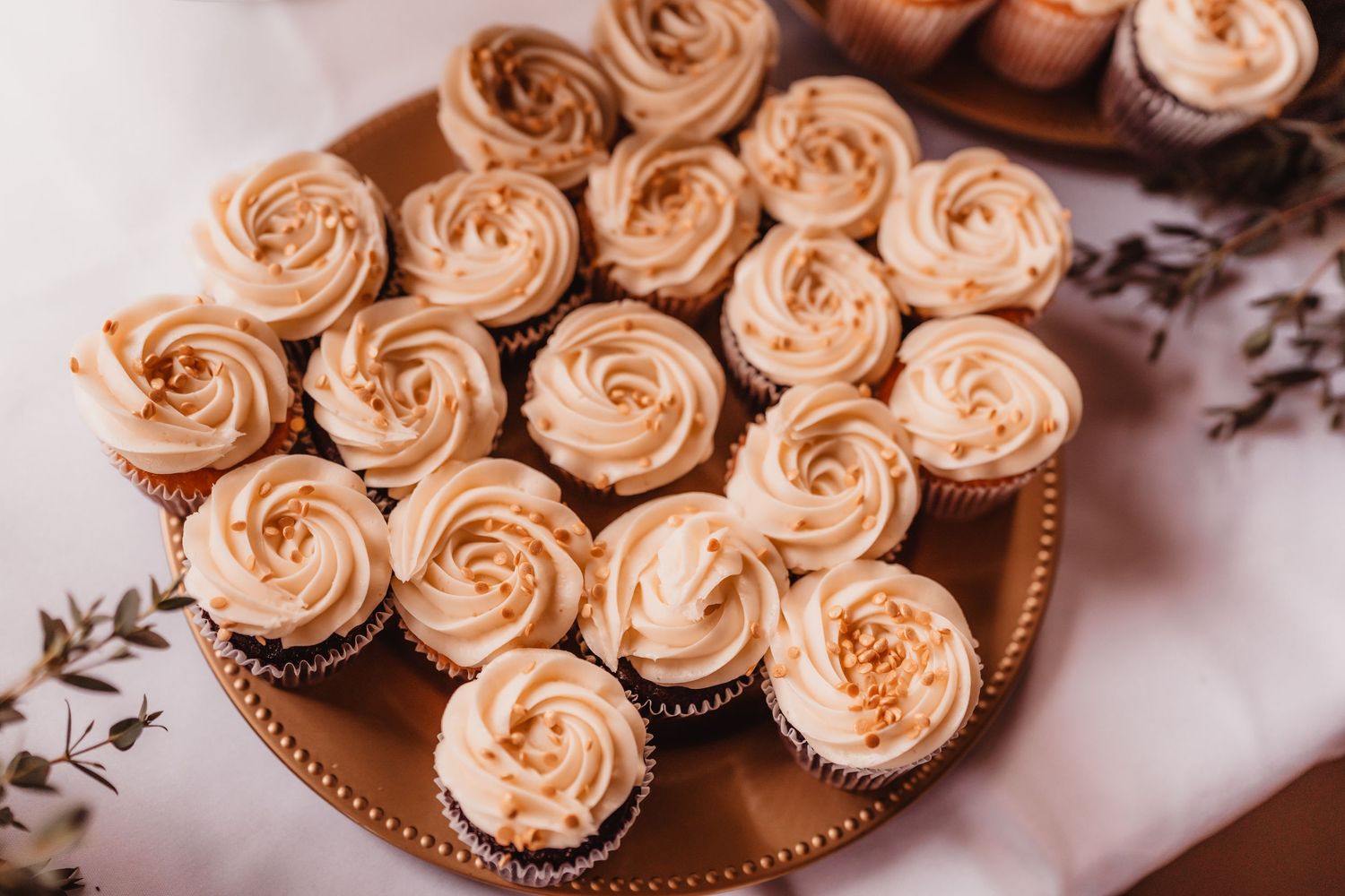 Tray of caramel frosted cupcakes with swirled rosette tops arranged for a wedding dessert table.