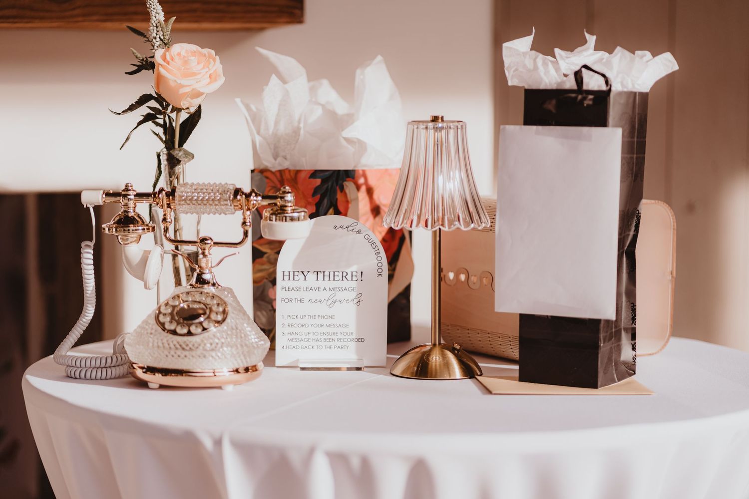 Vintage gold rotary phone and elegant lamp on a white tablecloth at a wedding reception.