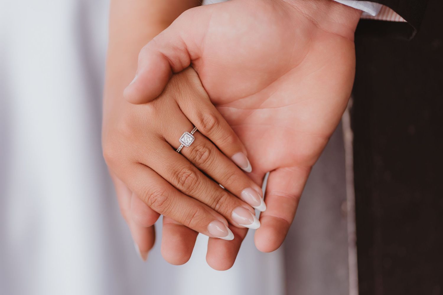 Detail shot of newlyweds holding hands displaying elegant square diamond wedding ring set.