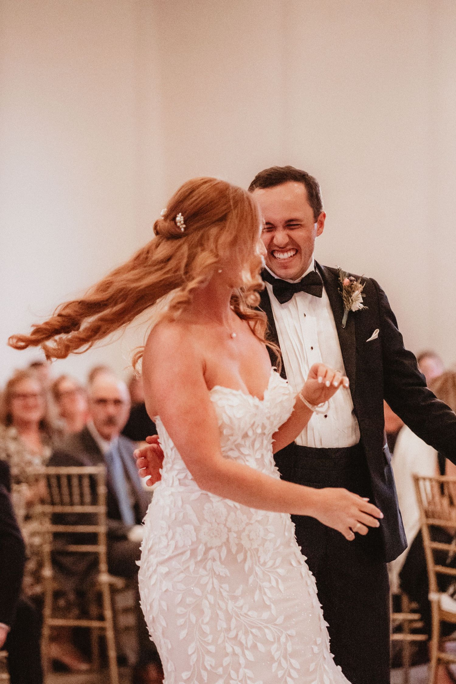Bride and groom laugh together during energetic first dance at reception.