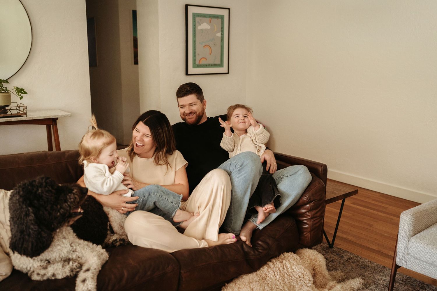 Happy family of four with a dog relaxing together on a brown leather sofa at home.