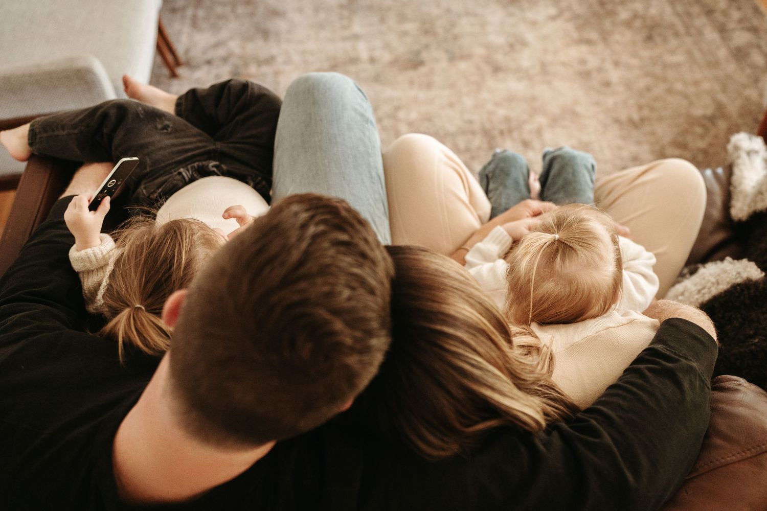 Overhead view of a couple and two young children lying together on a cozy floor.