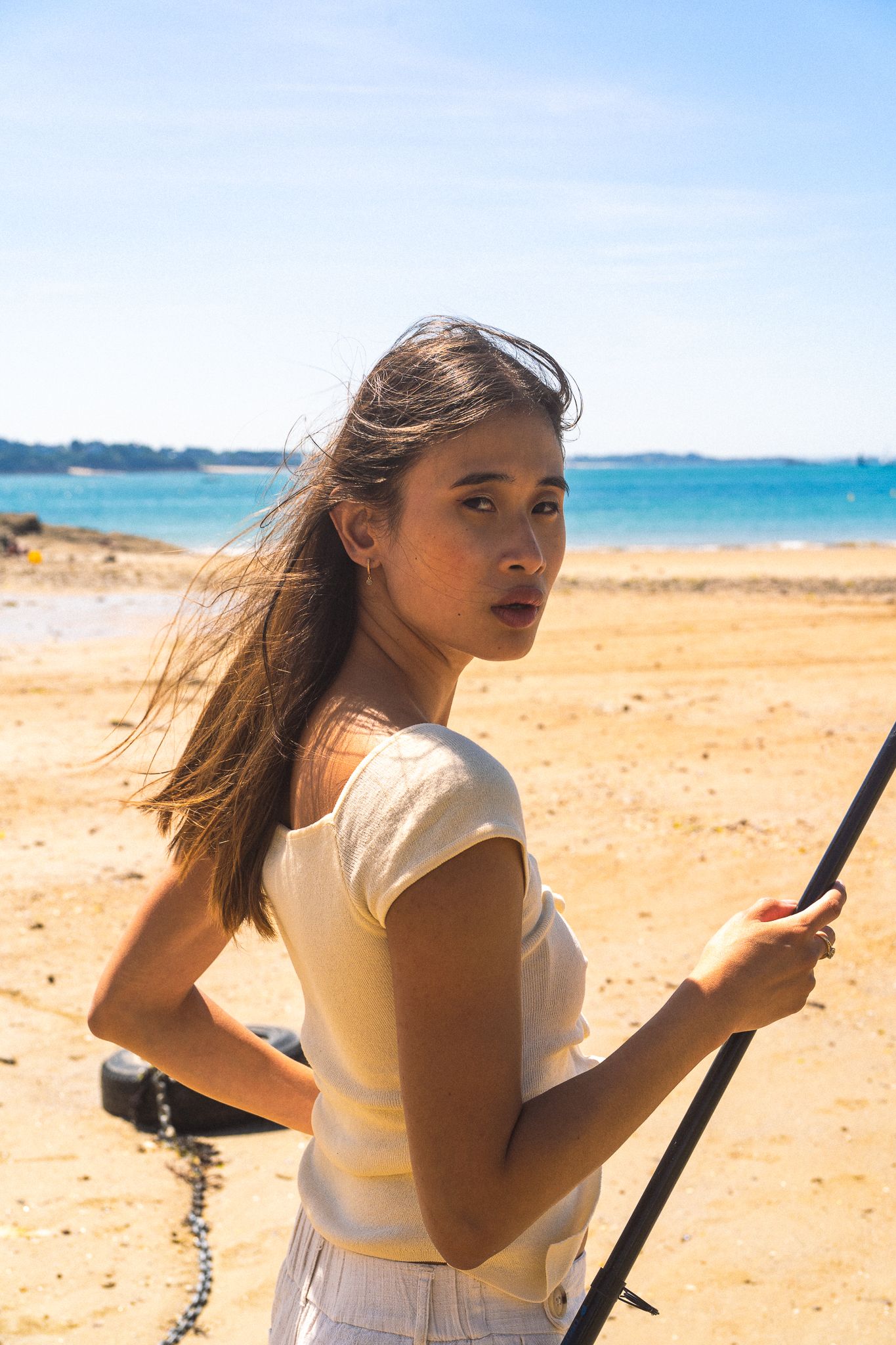 Portrait féminin élégant en lumière naturelle, expression douce et esthétique minimaliste. plage mer canne à pèche pour photo éditorial
