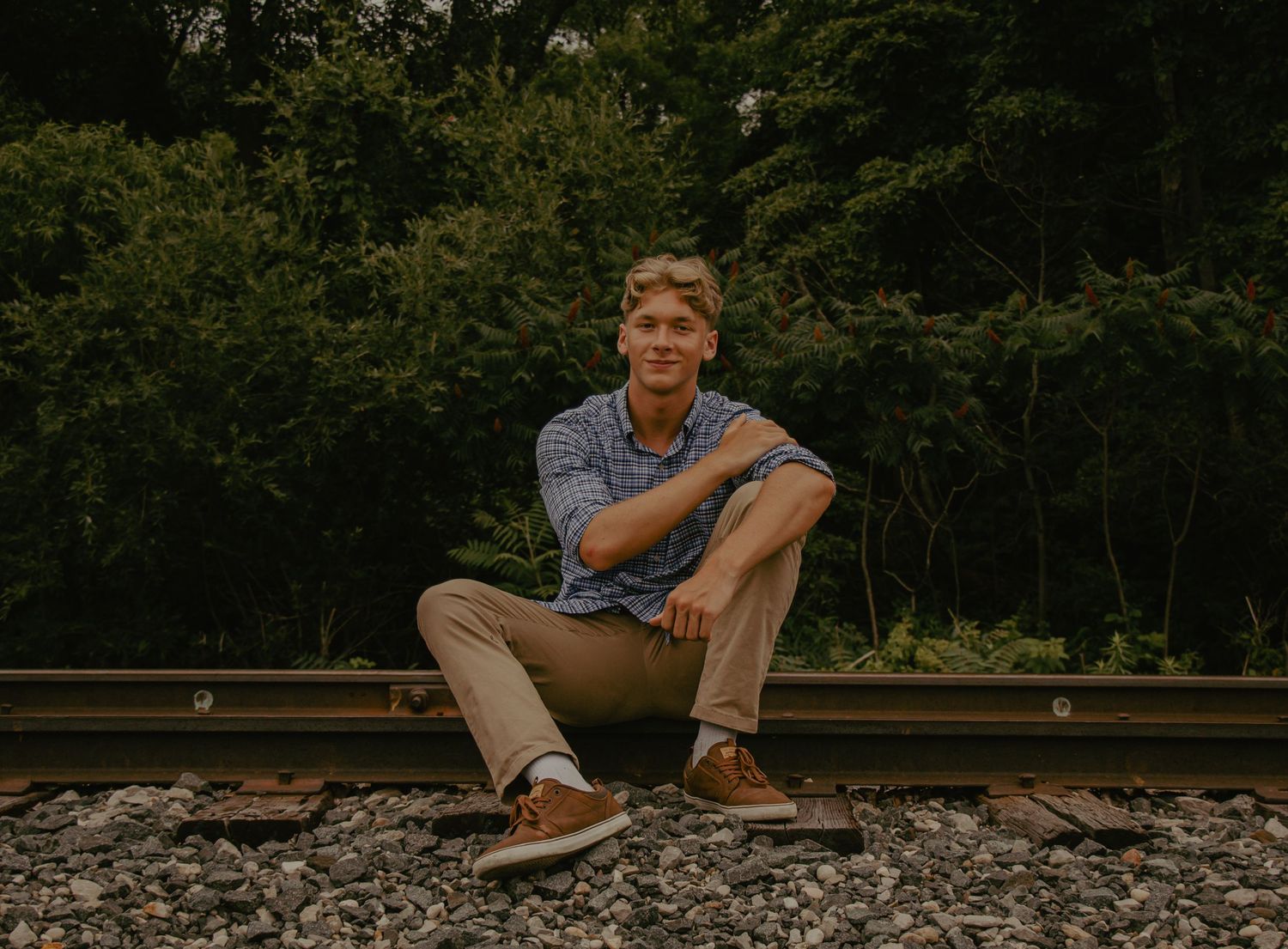 A series of panoramic shots showing a person walking and sitting on railroad tracks at sunset.