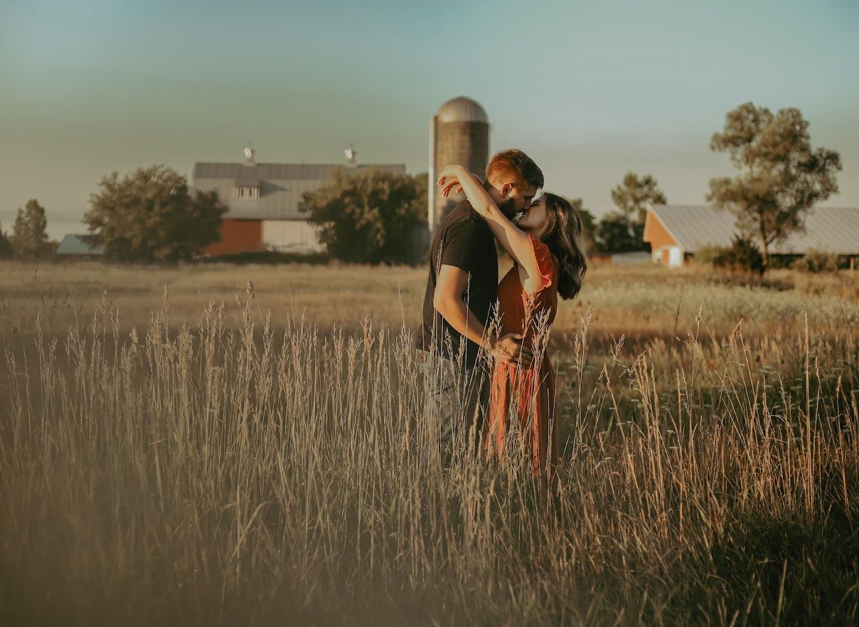 People walking through tall grass field during golden hour sunset.