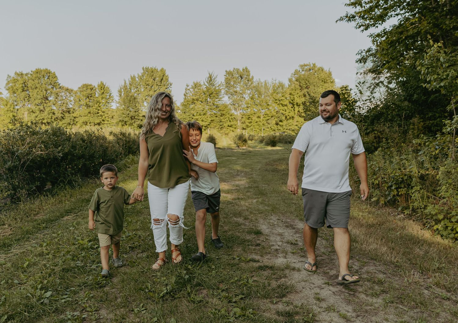 Family walking together on natural trail during summer evening.