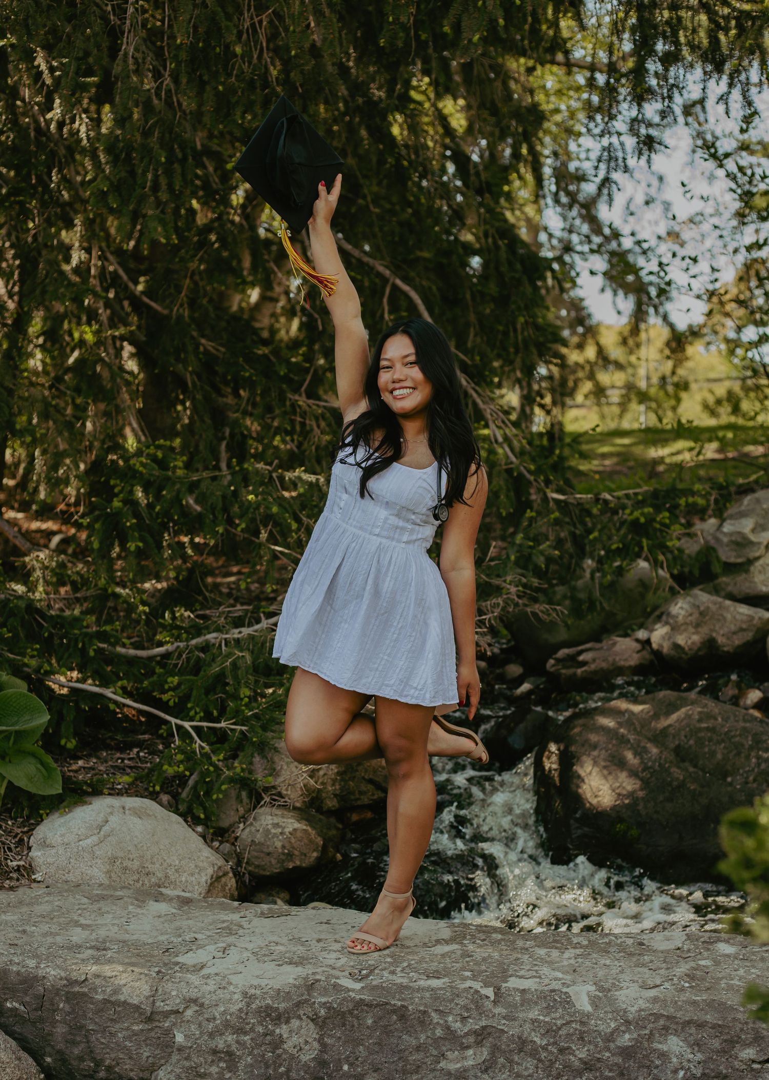 Person sitting on large rocks surrounded by greenery and trees.