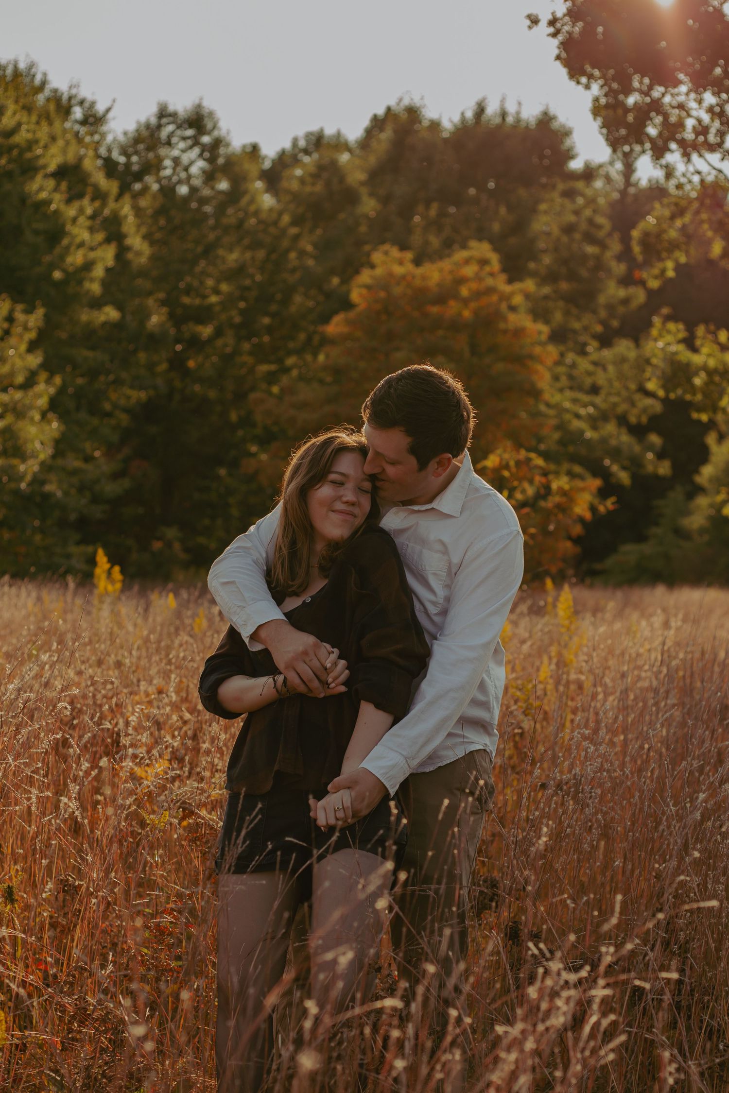 Two people share tender moments in a sun-lit autumn field.