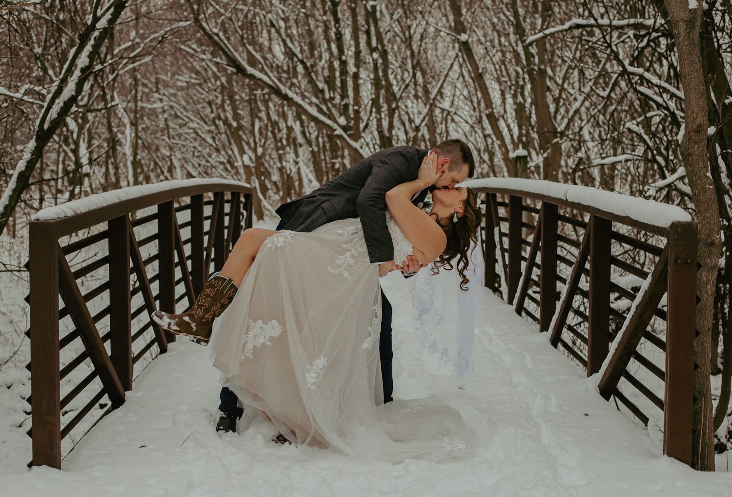 A romantic winter scene with a couple on a snow-covered wooden bridge.