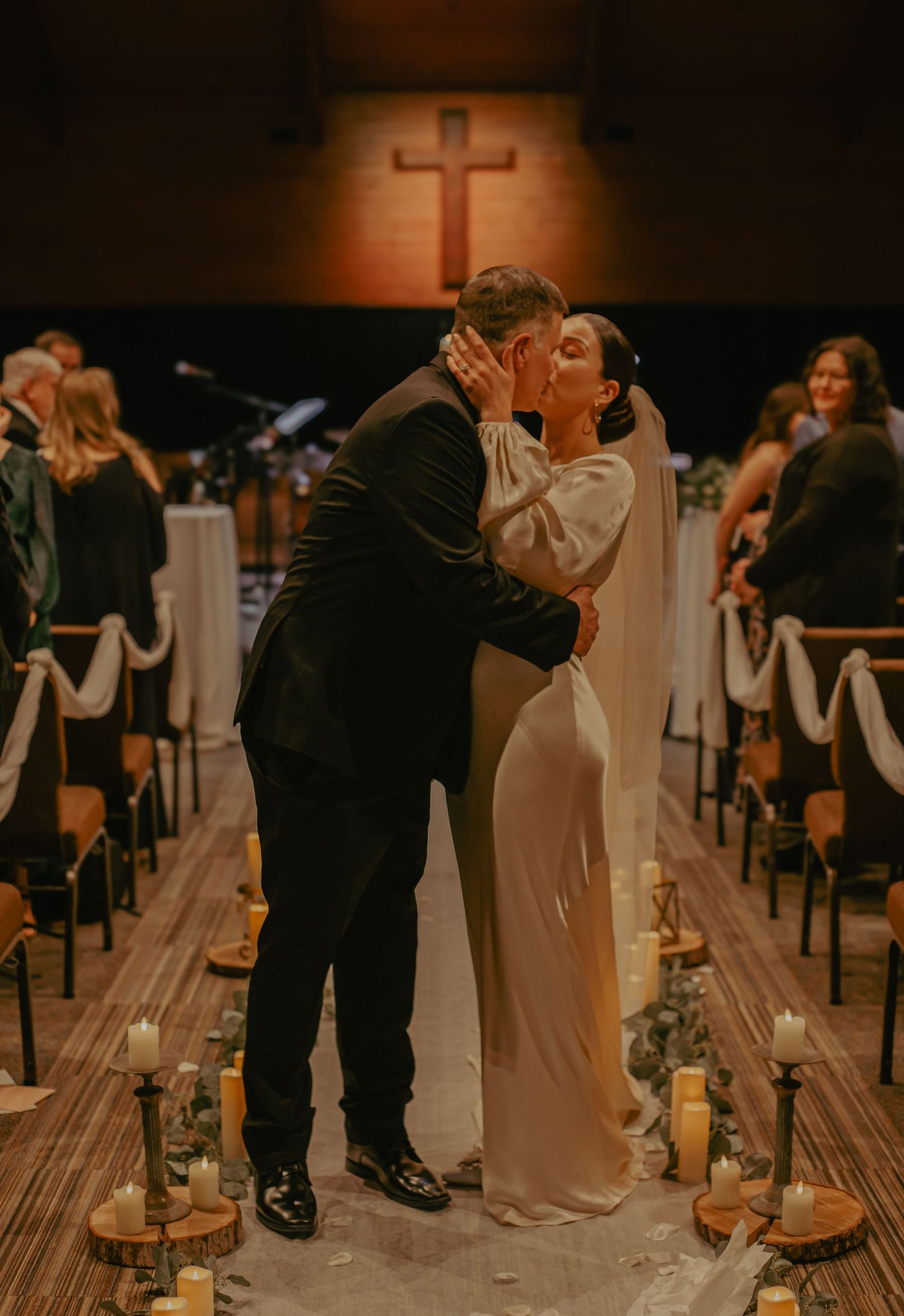 A romantic candlelit wedding ceremony in a dimly lit church with wooden floors.