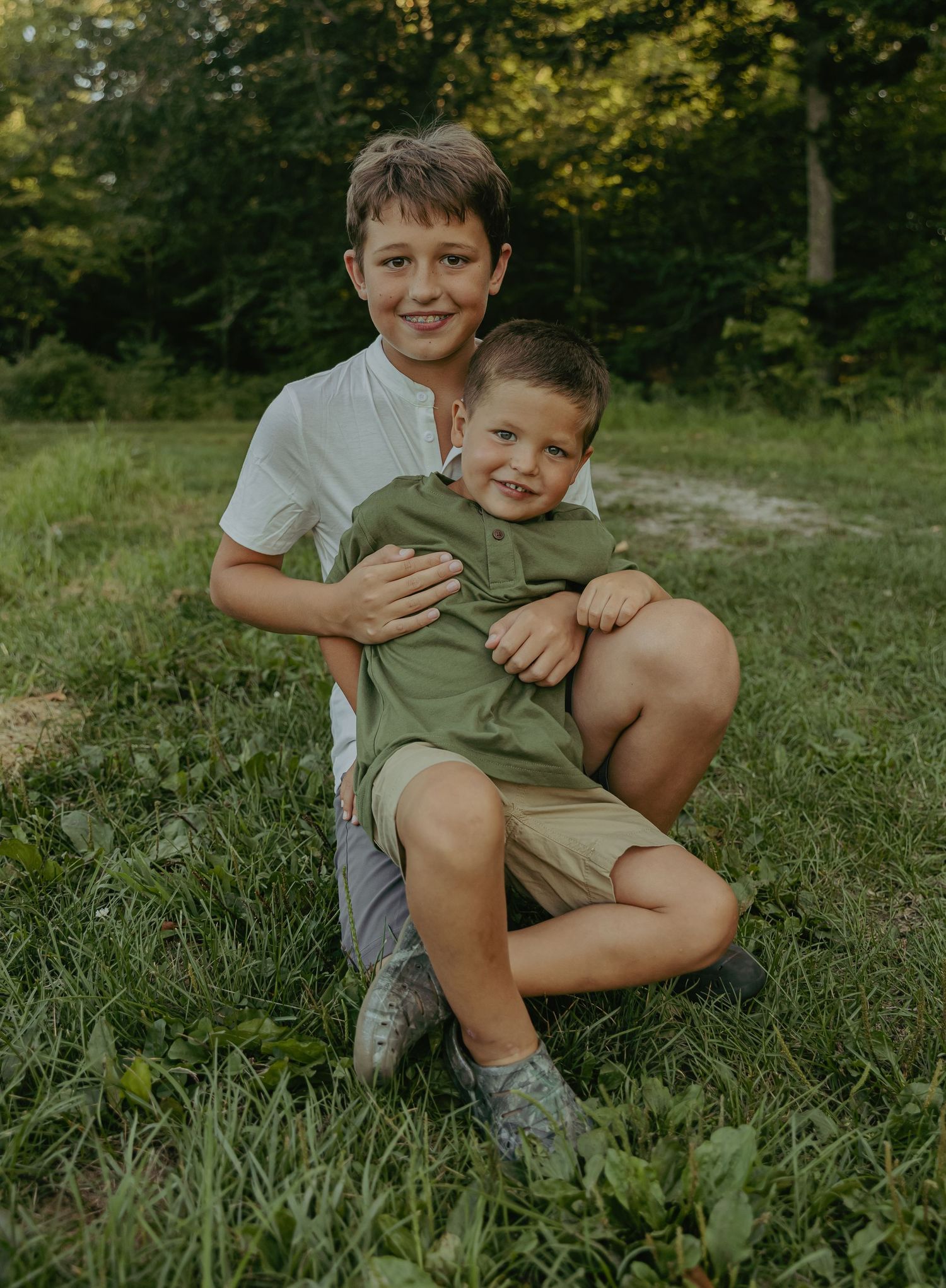 Two young boys sharing a playful moment in grassy outdoor setting.