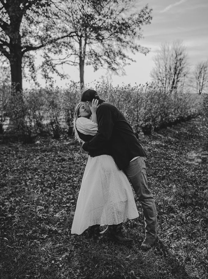 Black and white romantic moment captured on hill covered with fallen autumn leaves.