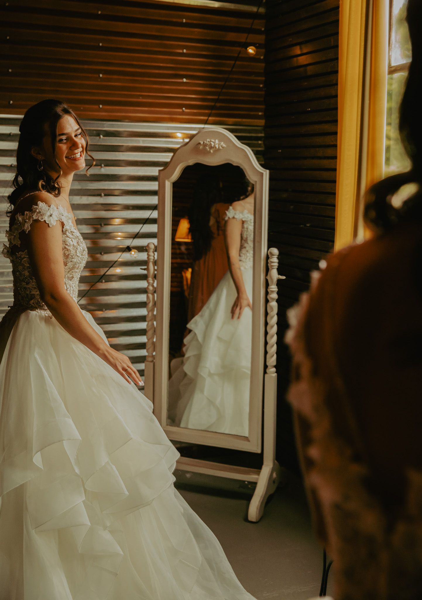 Wedding dress detail with reflection in vintage mirror against rustic background.