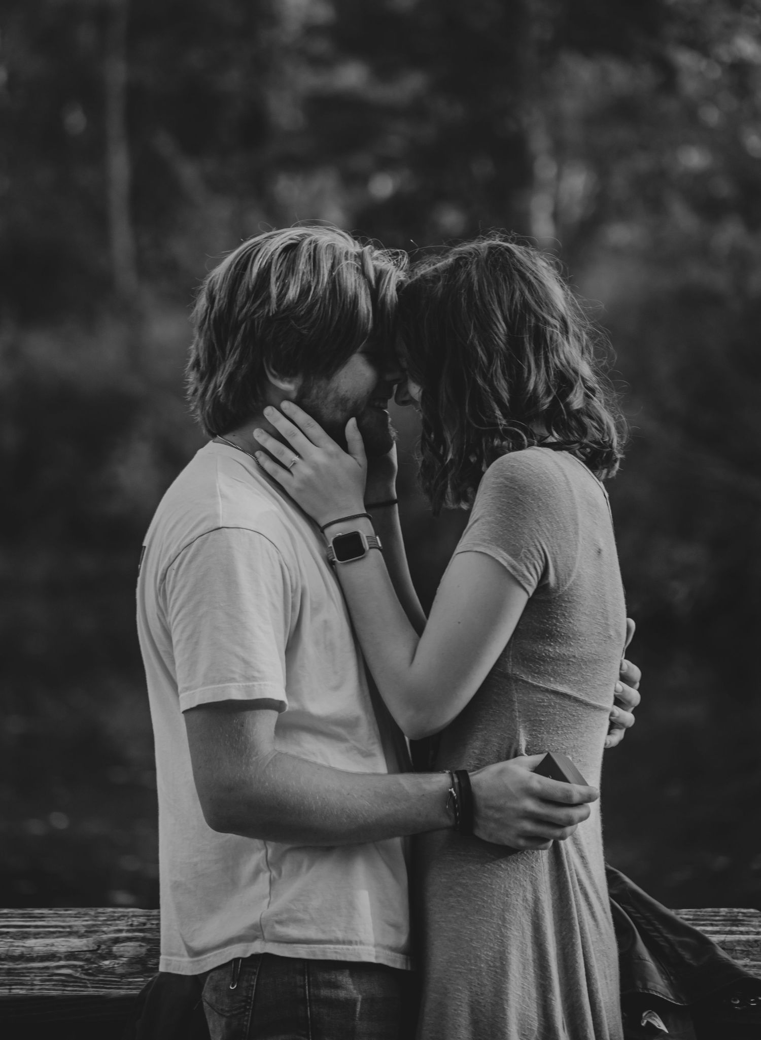 A black and white intimate portrait captured on a wooden deck.
