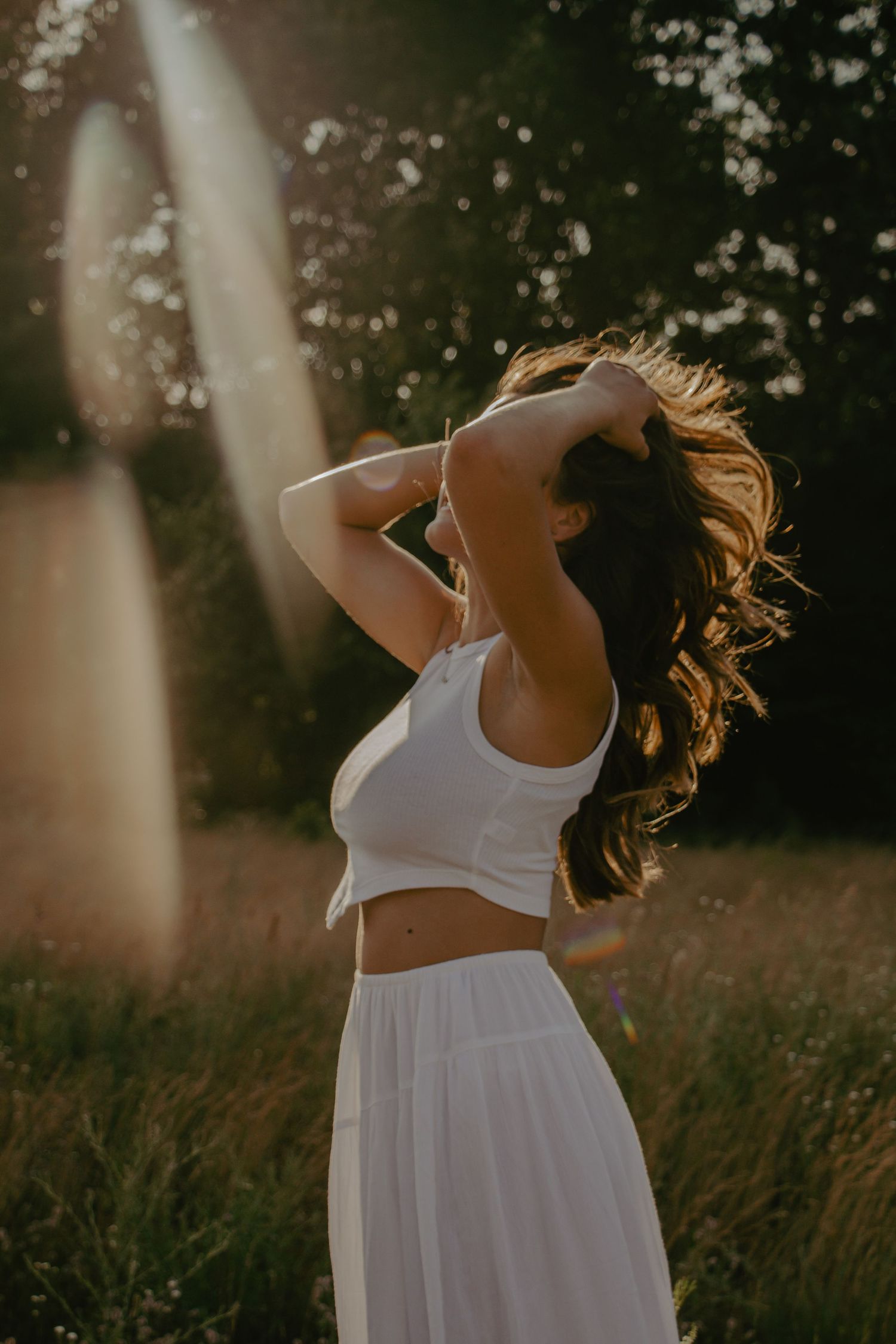 White dress flowing in sunlit field during golden hour.