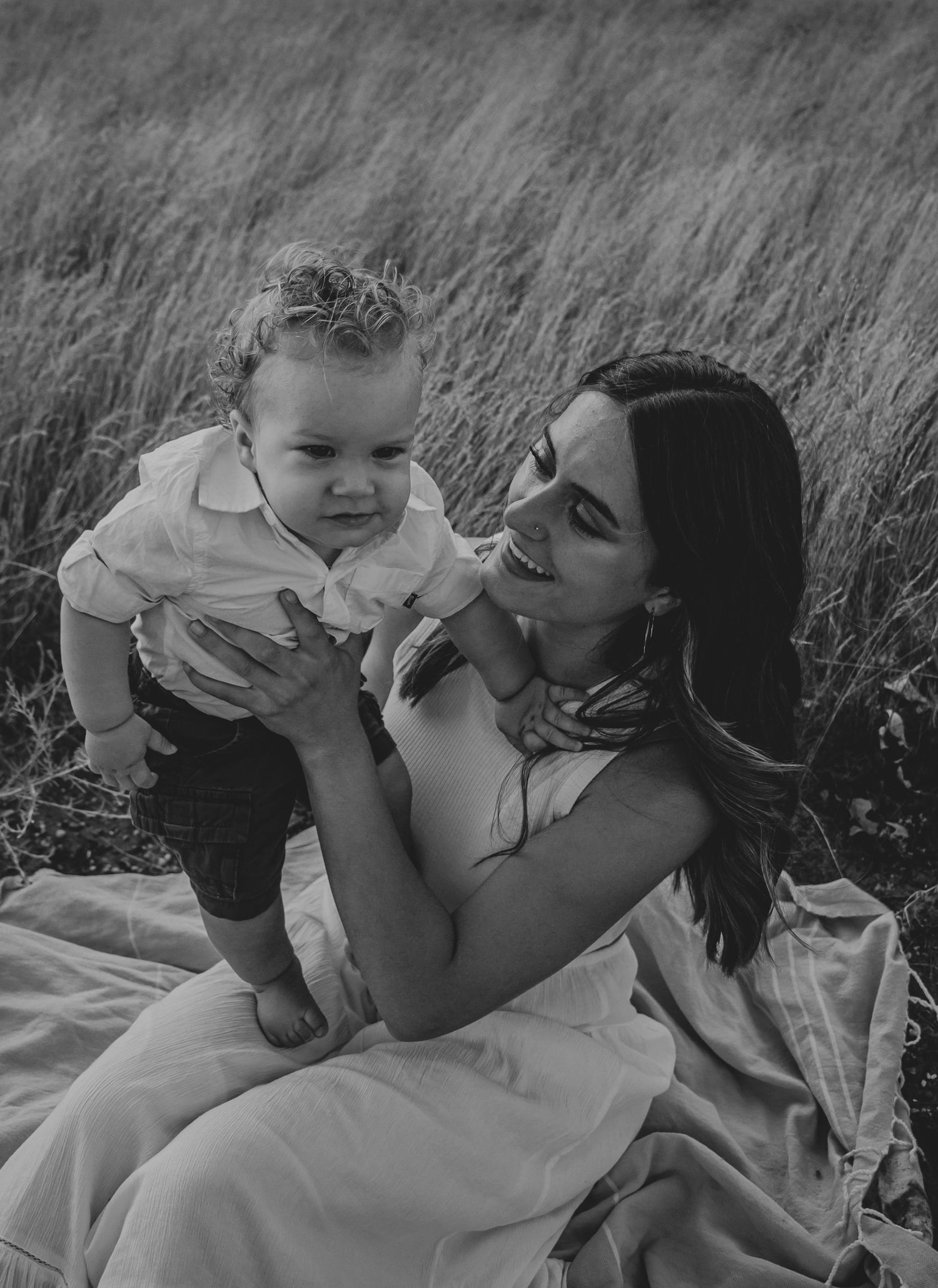 Black and white photo showing a tender moment of affection in a grassy field.