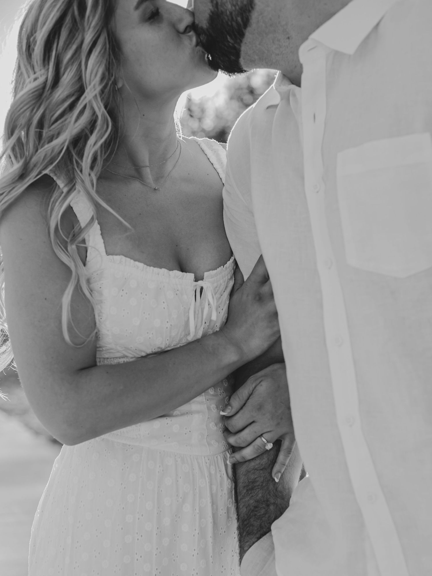A romantic black and white portrait of a couple in intimate embrace.