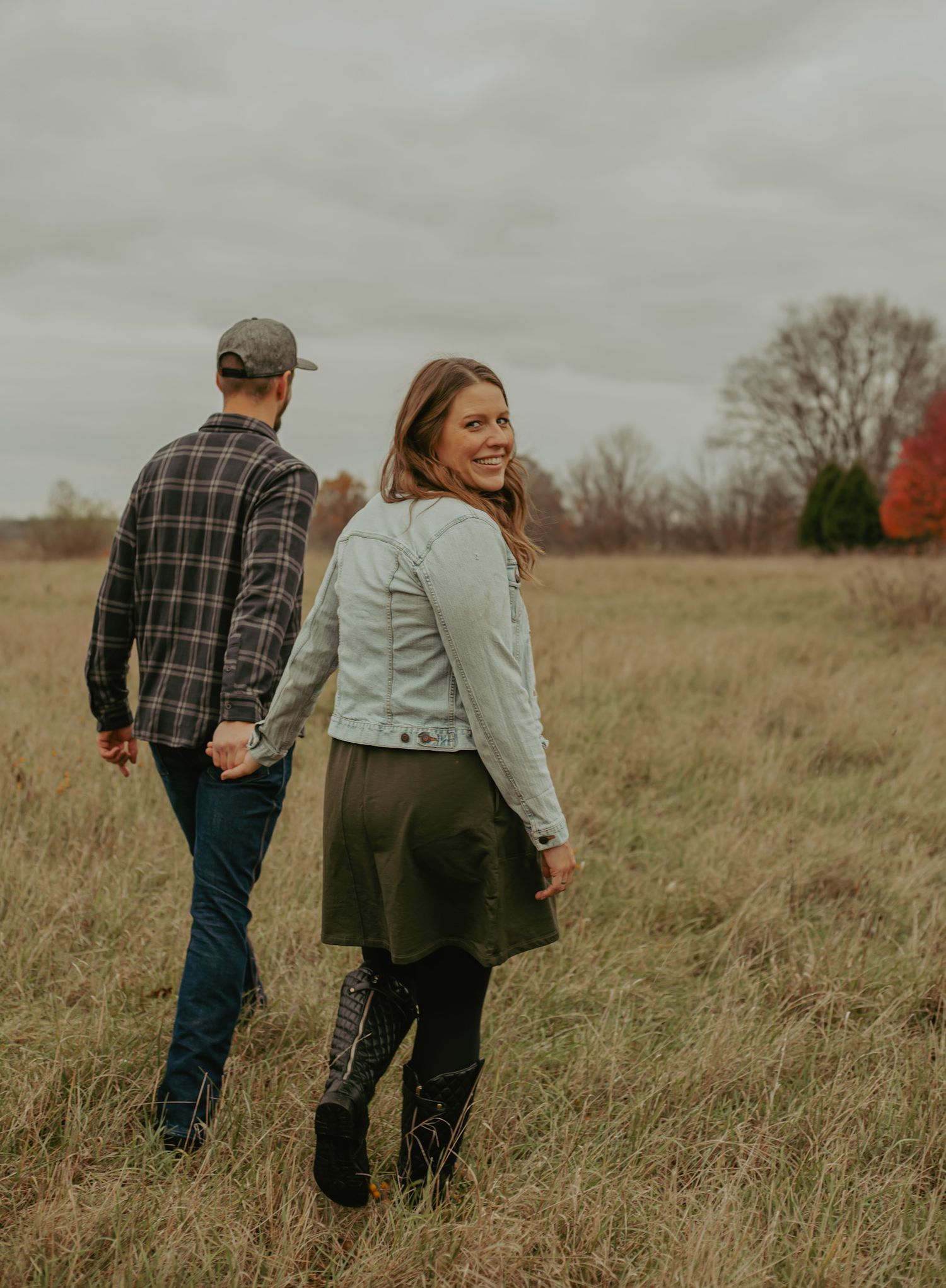 A couple walks together through a golden autumn field during sunset.