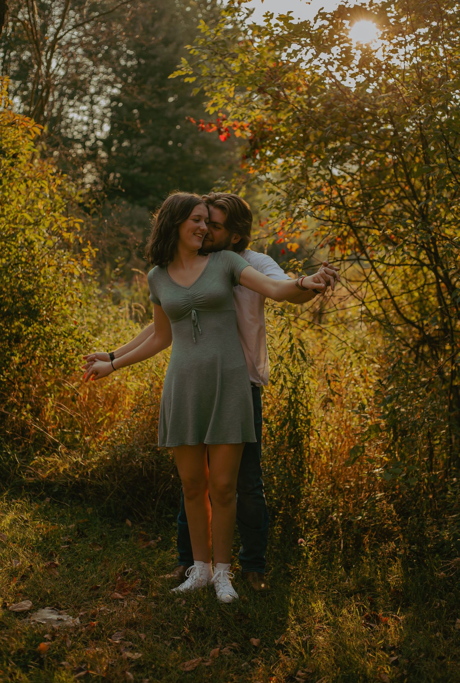 A couple embraces among golden fall foliage during sunset.
