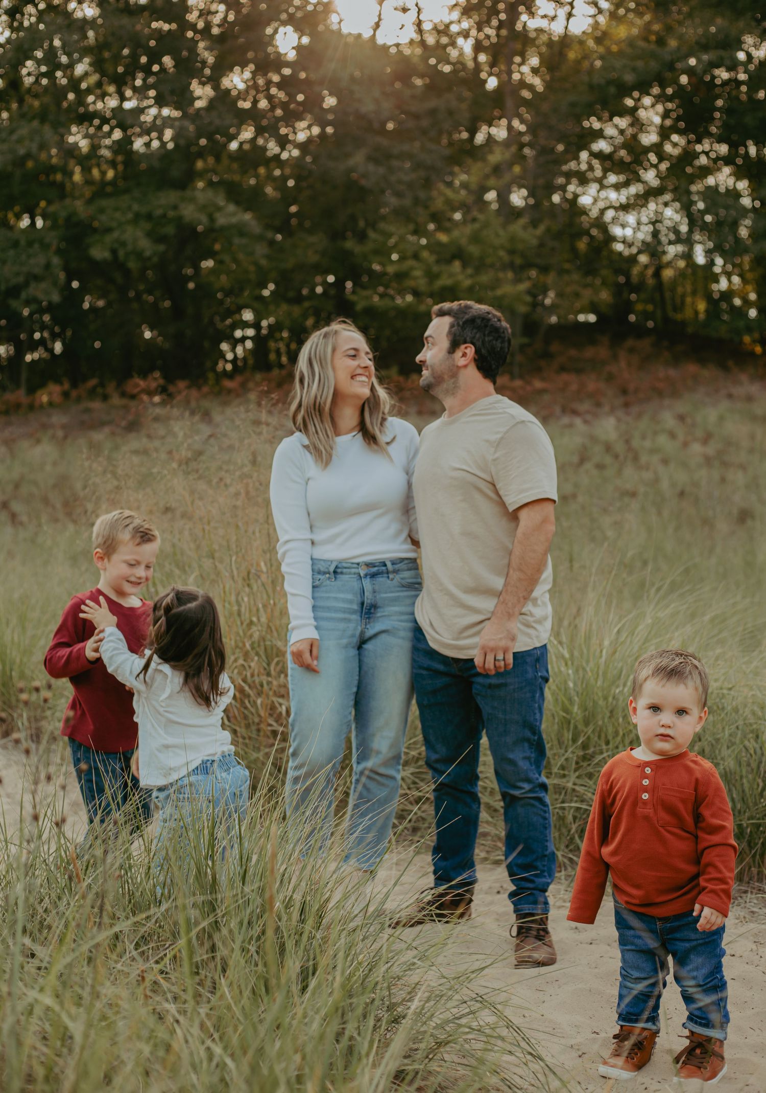 Family enjoying playful moments together in a golden grass field during sunset.