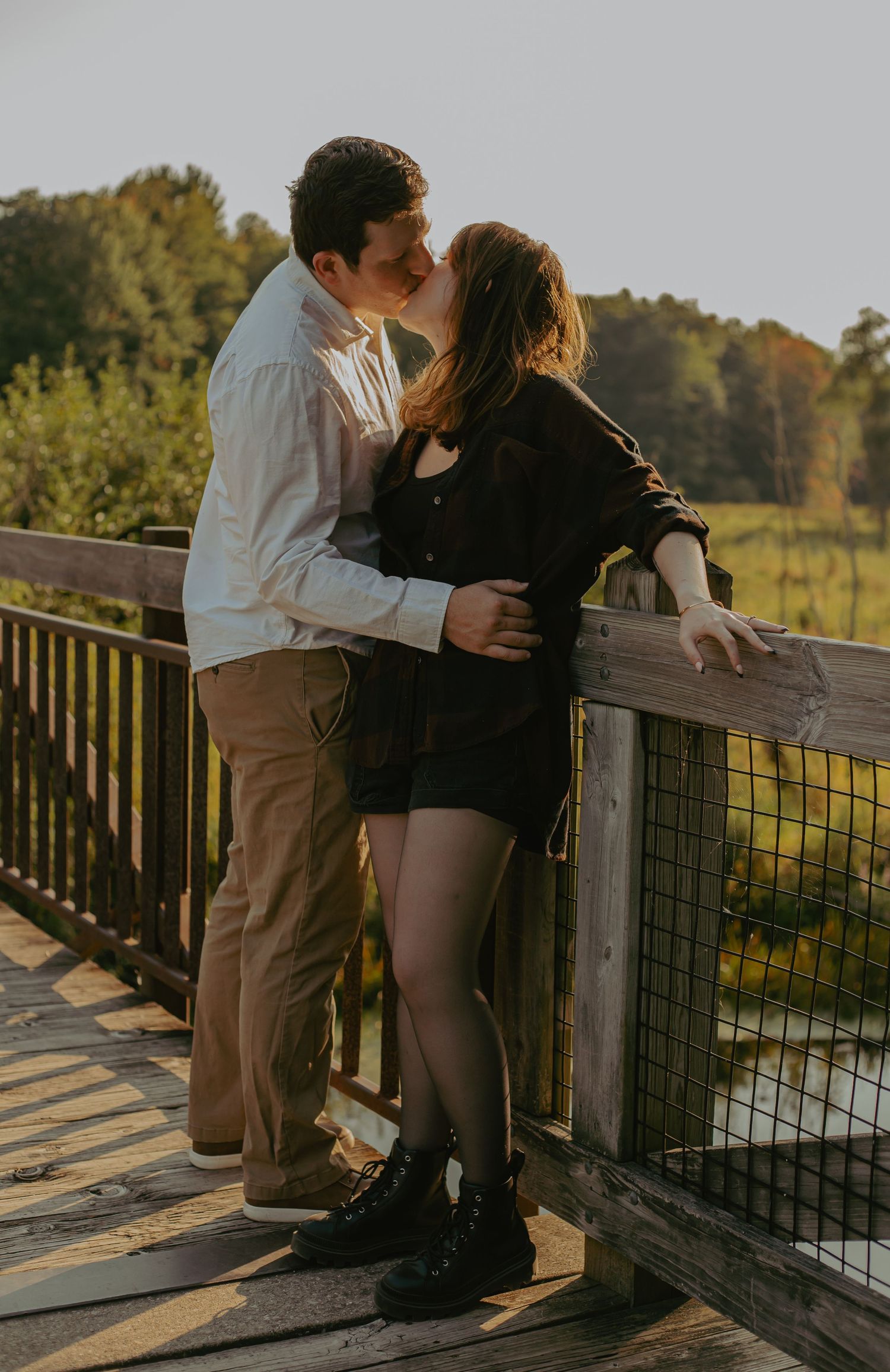Romantic couple embracing on a wooden deck during golden hour.
