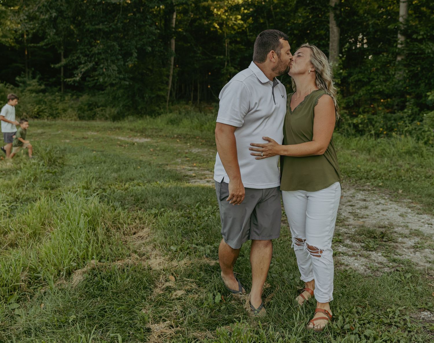 Couple sharing intimate moment on nature trail during summer evening.