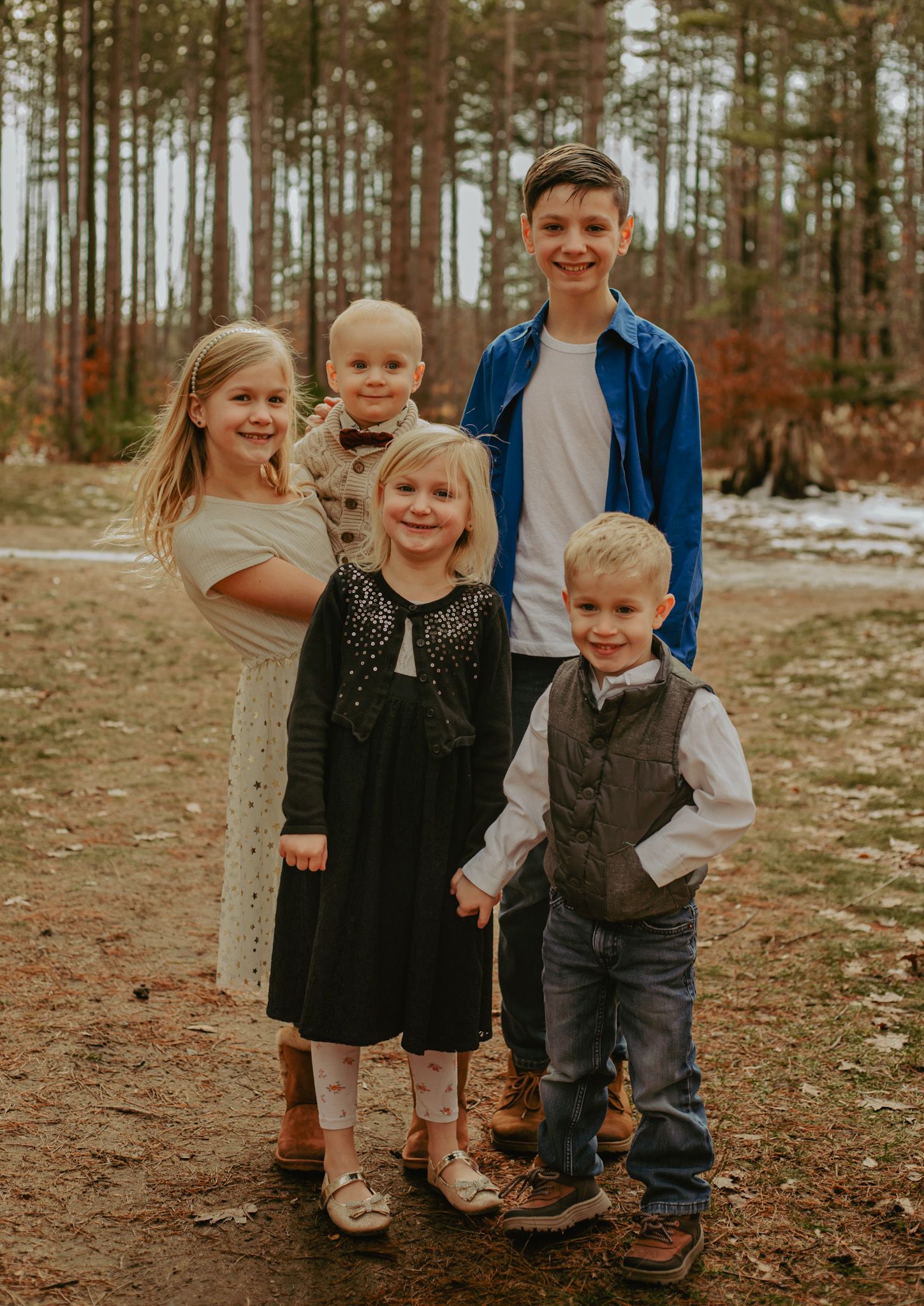 Children posing together on forest trail during autumn family photoshoot.