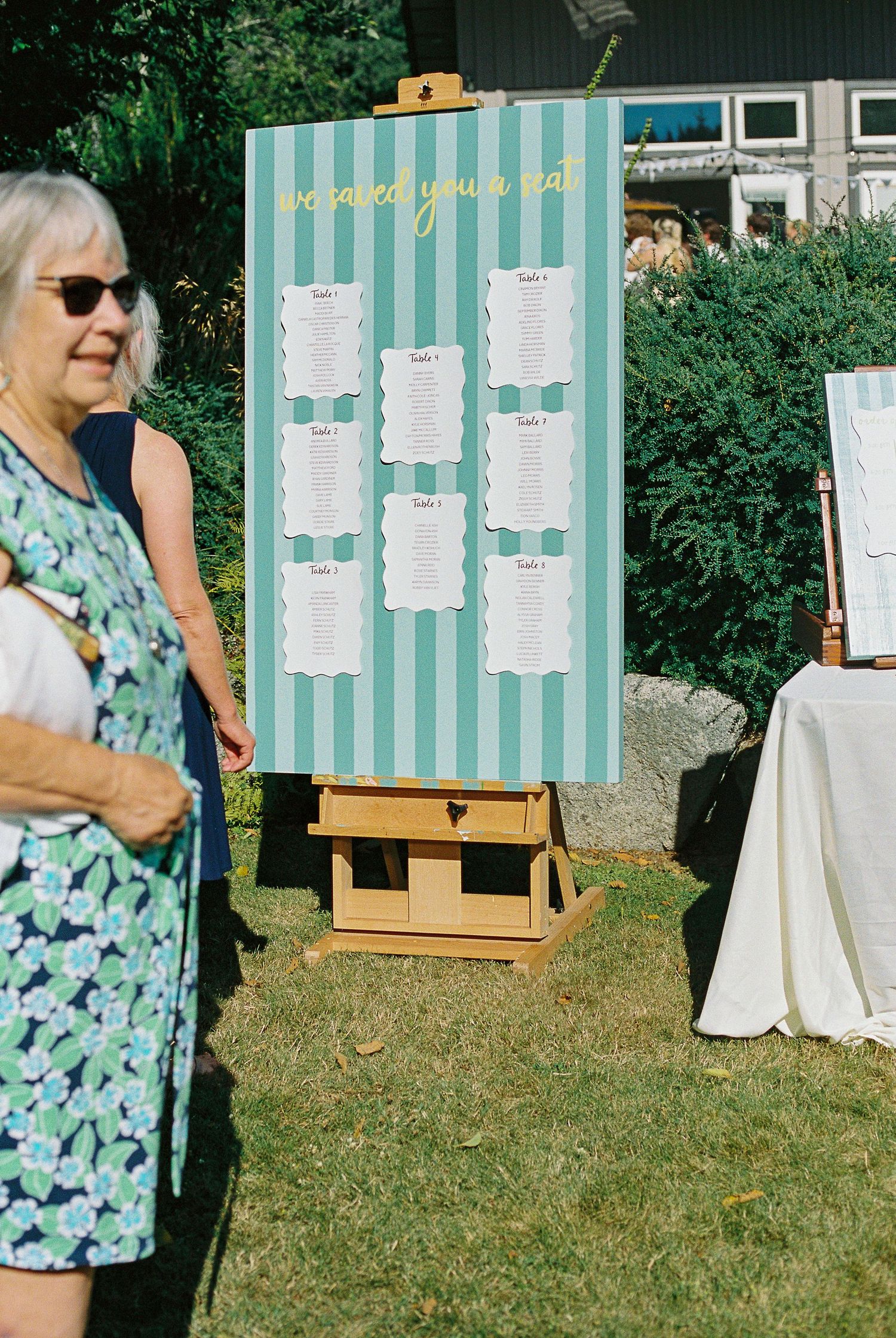 Outdoor wedding seating chart on easel with teal stripes and \