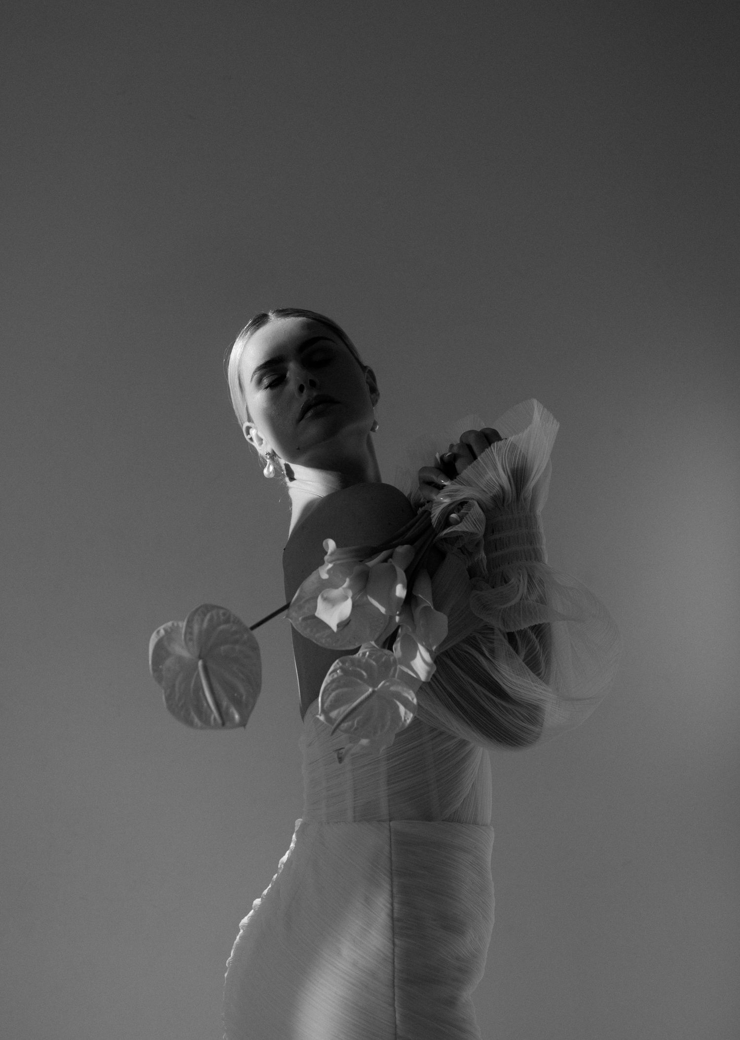 Dramatic black and white photo of a person in a wedding dress with flowing fabric details.