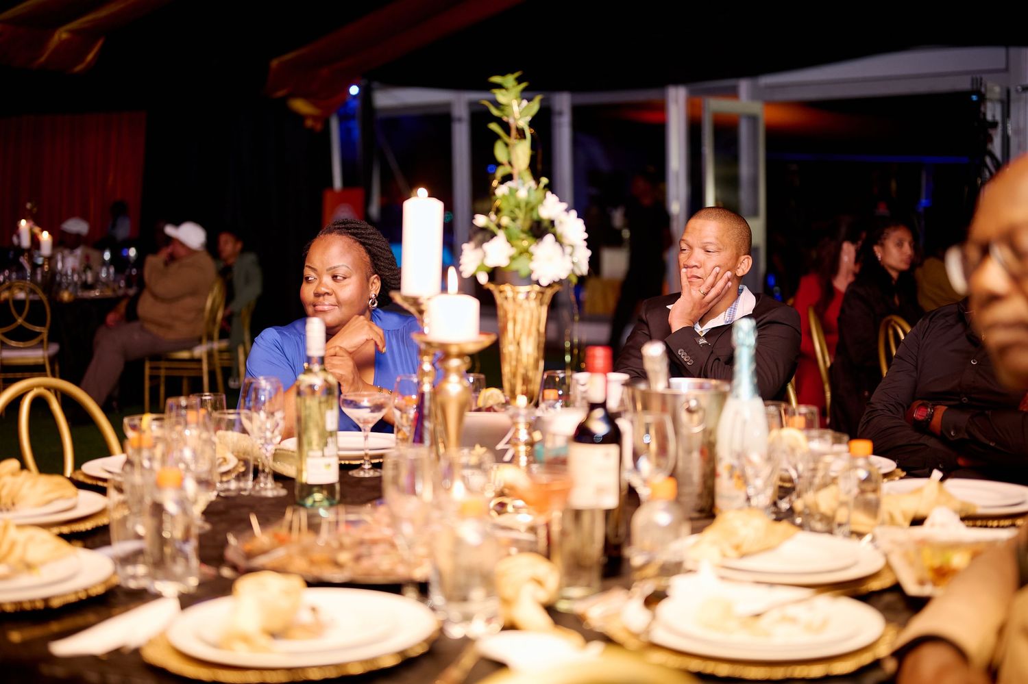 Guests seated at elegantly decorated dinner table with candelabra centerpiece at a formal evening event.