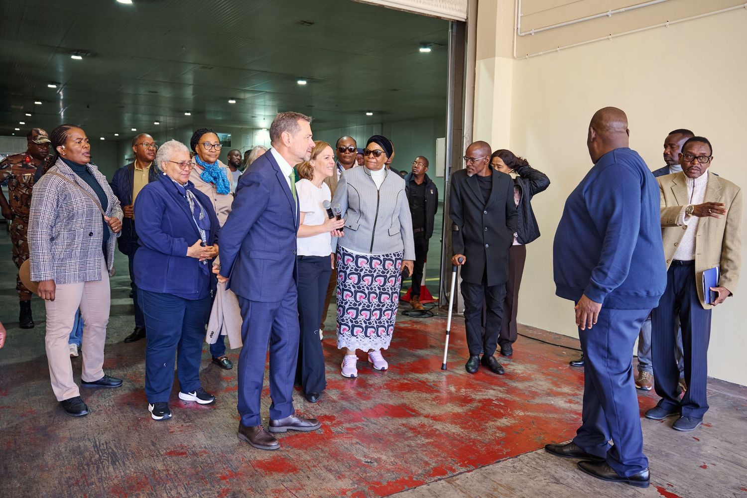 Group of diverse professionals in formal attire gathered outside a modern building entrance for an official meeting.