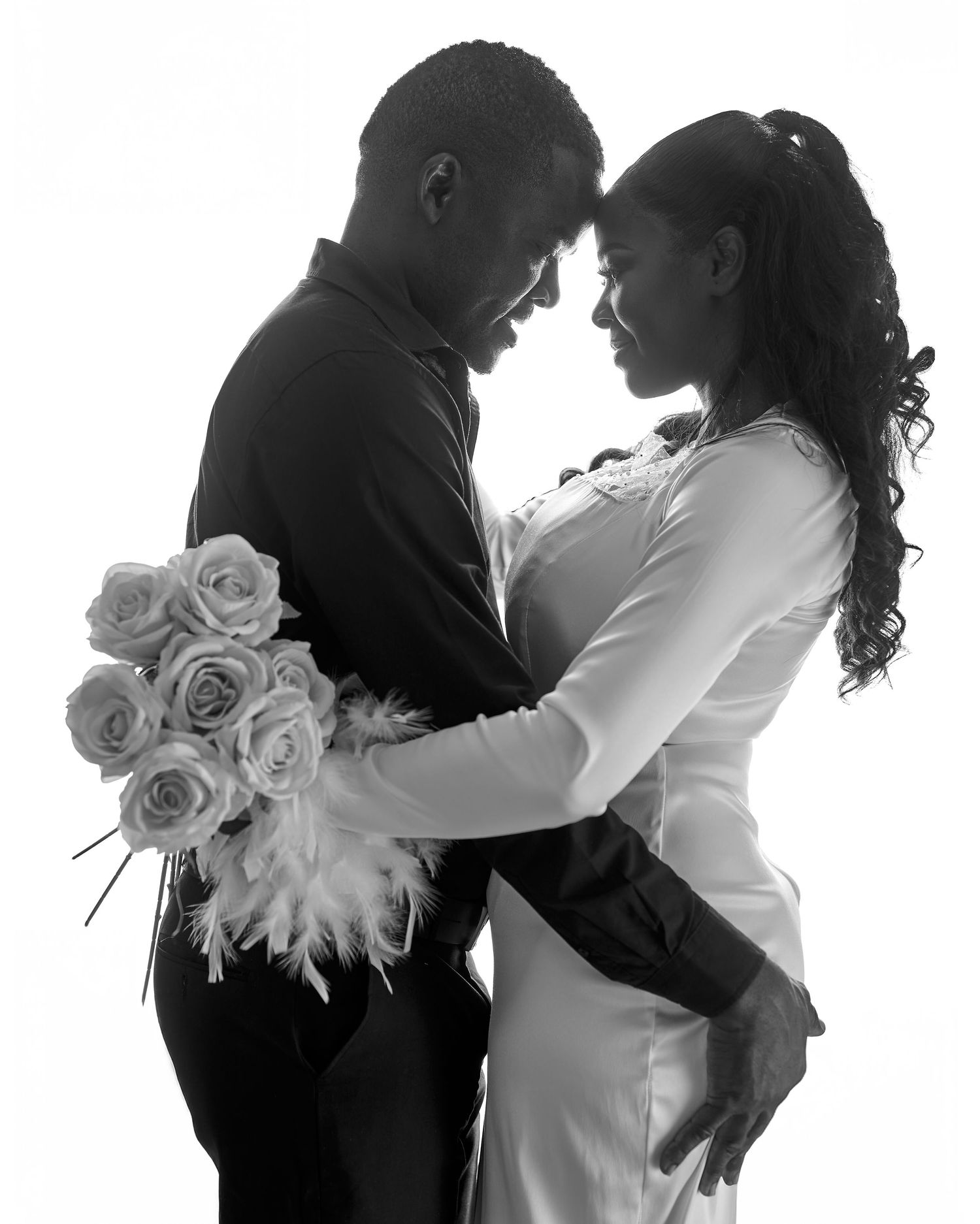 Black and white artistic wedding photo series showing intimate silhouettes of a couple with white roses.