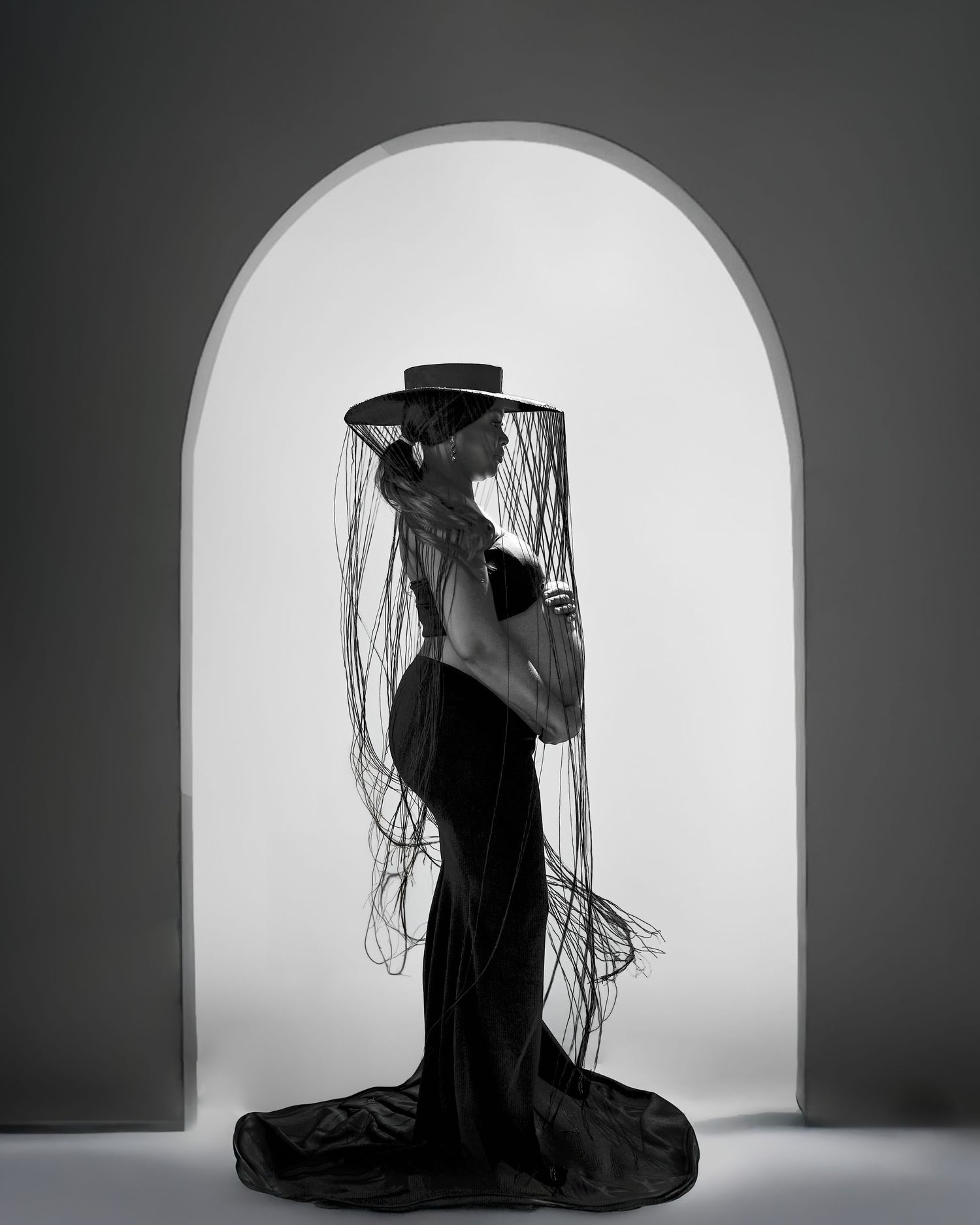 A dramatic black and white photo series showing a silhouetted figure in a hat against an arched white backdrop.