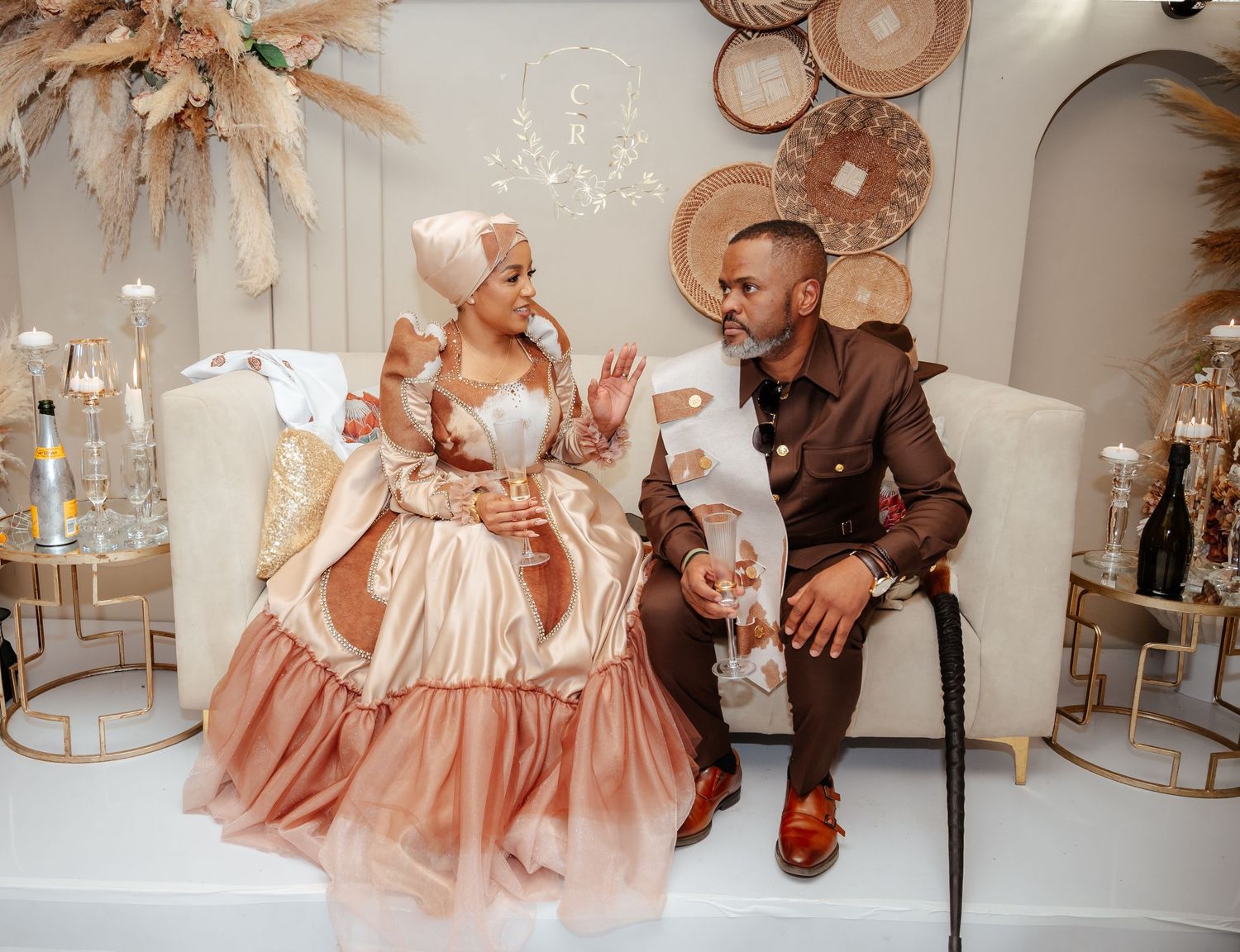 Elegant couple in traditional African attire seated together at a beautifully decorated wedding celebration venue.