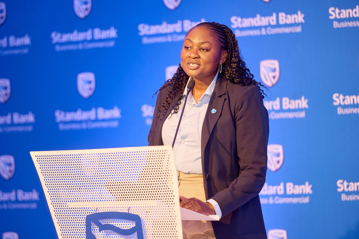 Woman speaking at Standard Bank Business & Commercial podium during a professional corporate event.