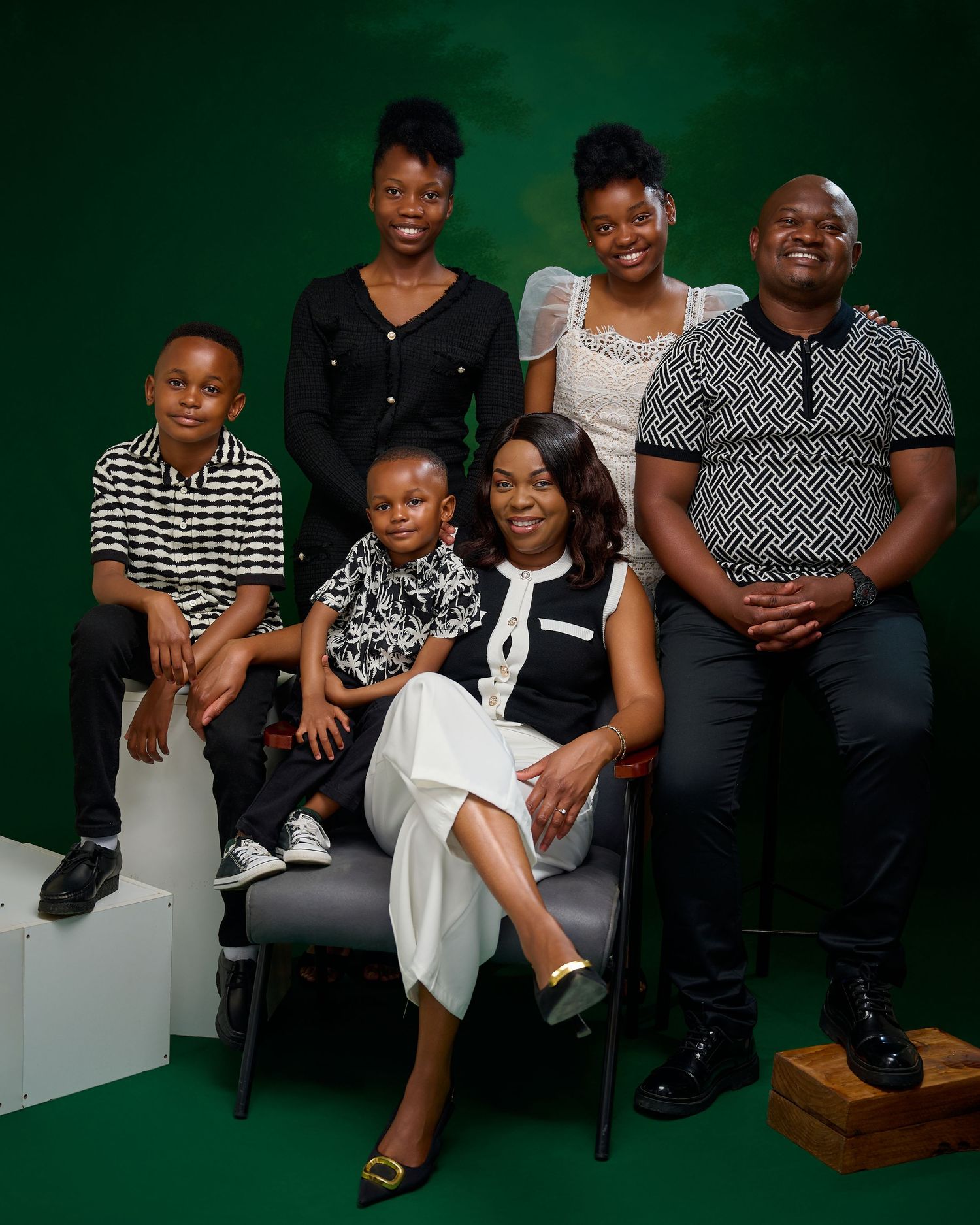A family portrait series against a dark green background showing candid moments and warm smiles in black and white outfits.