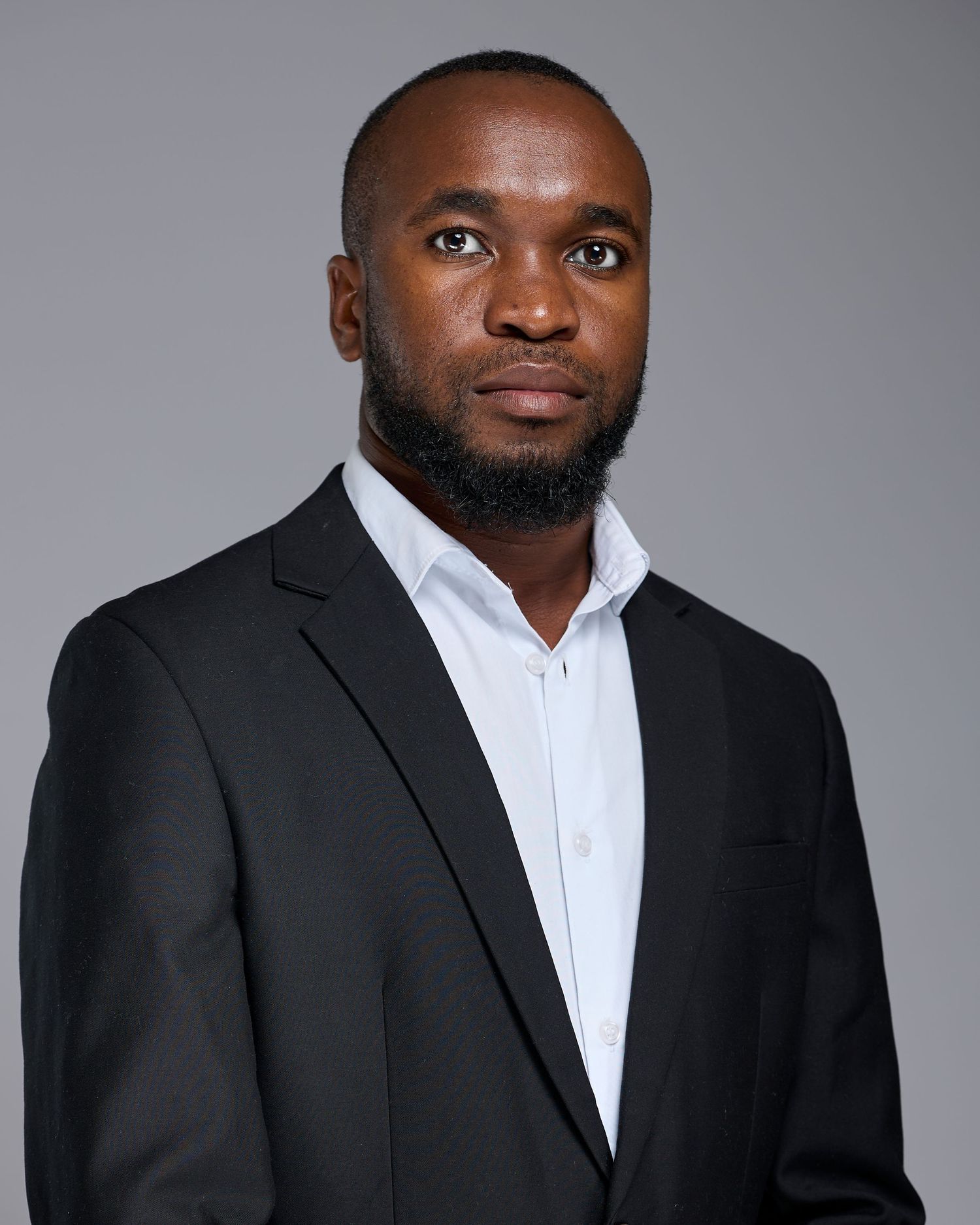 Professional headshot portrait series of a person in a black suit and white shirt against a gray studio background.