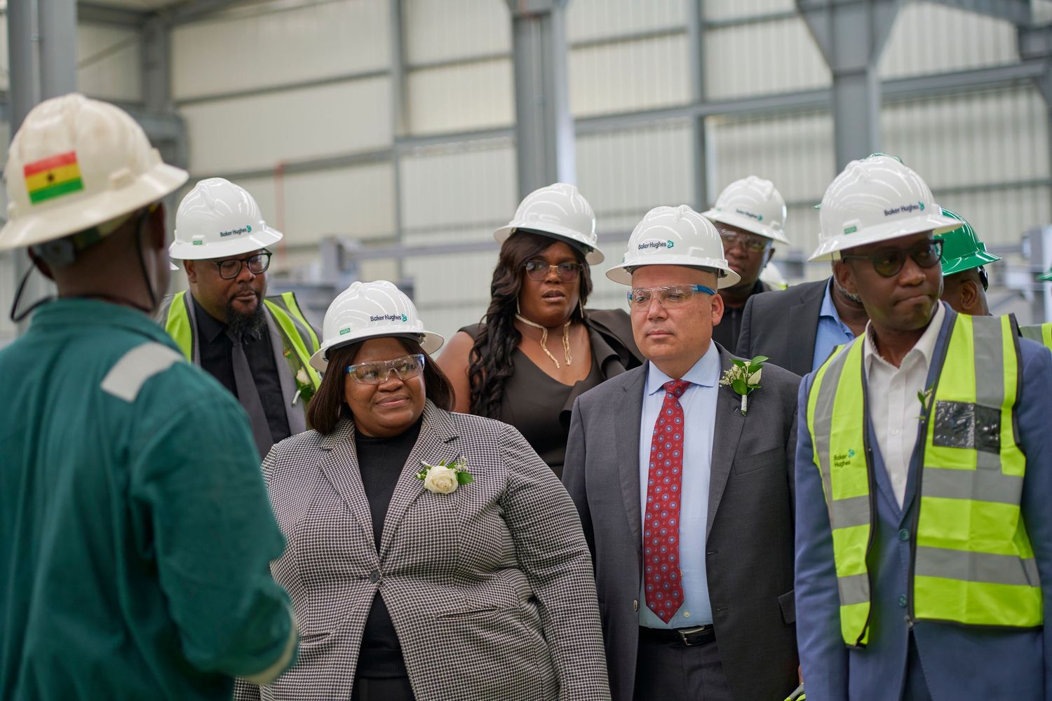 Group of professionals in white hard hats touring an industrial facility during a formal inspection visit.
