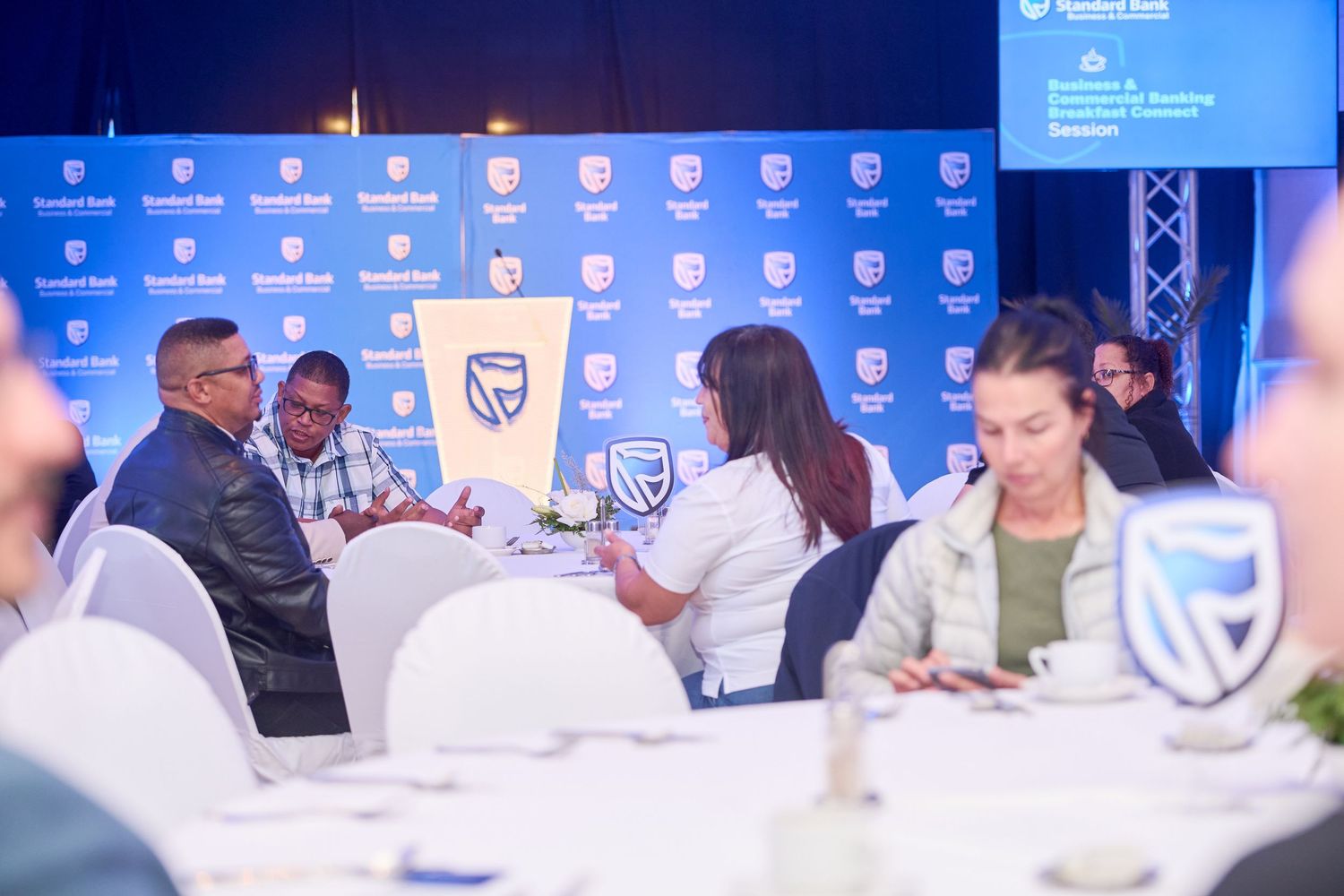 Standard Bank business event with professionals engaged in discussion at a branded conference table.
