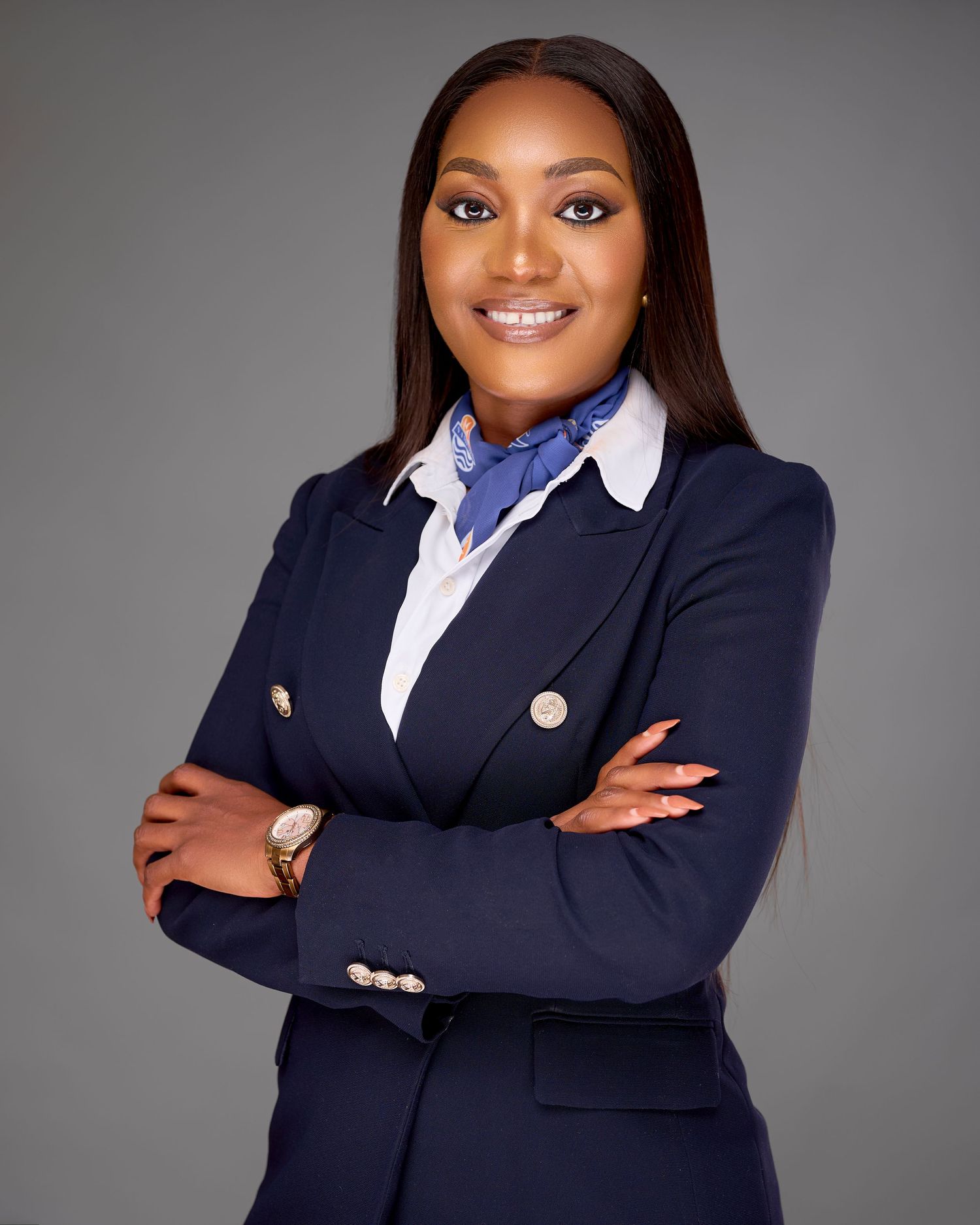 Professional business portrait in navy blazer with white collar against grey backdrop showing confident pose.