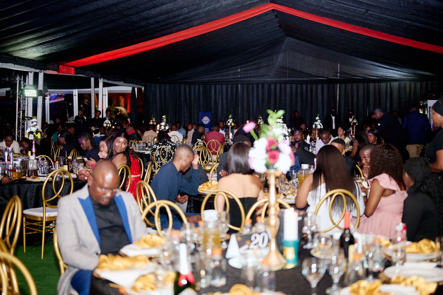 Guests dining at an elegant black and red themed gala event with decorated tables and centerpieces.
