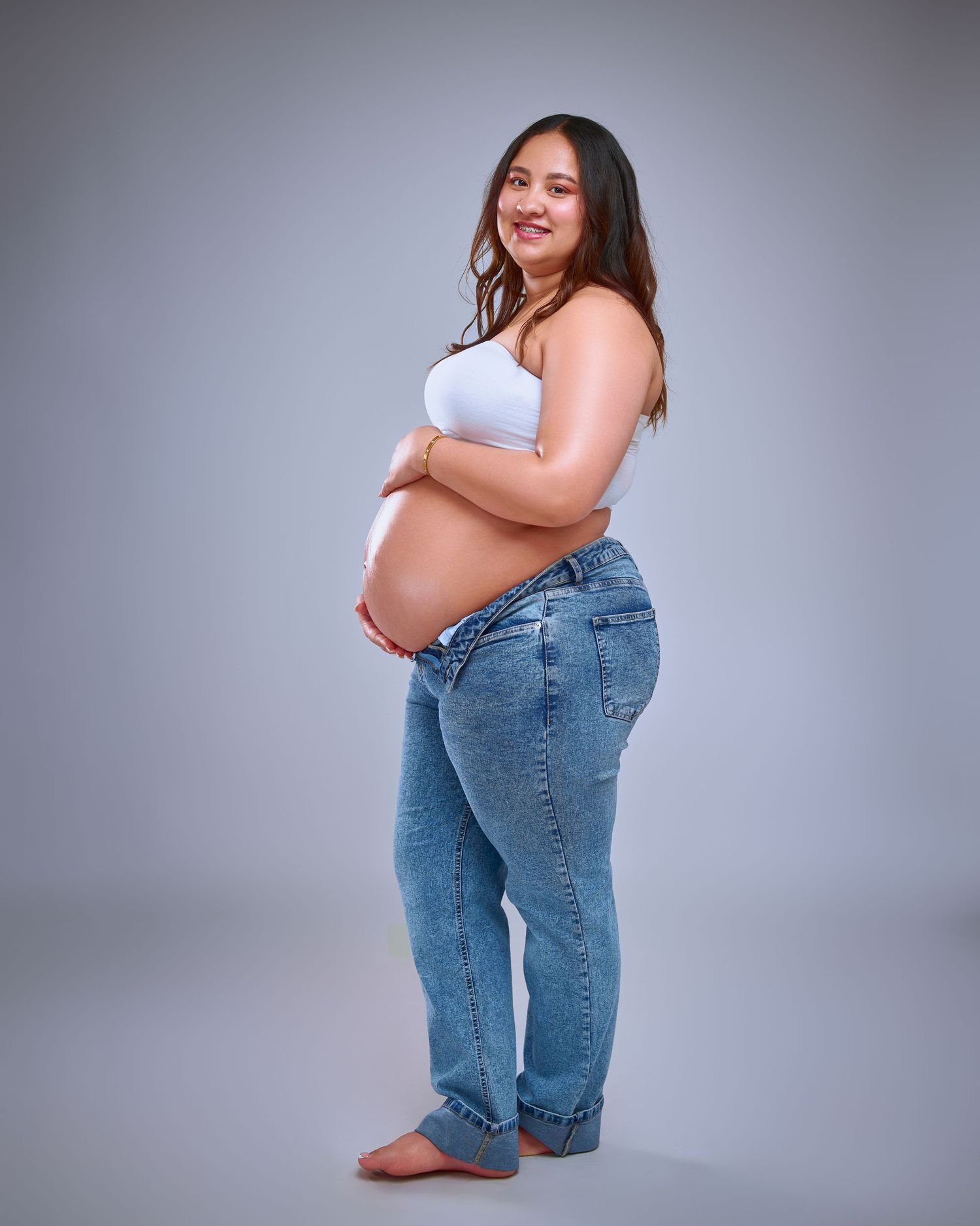 A woman in blue jeans and white top poses in a series of photos showing weight loss transformation progress.