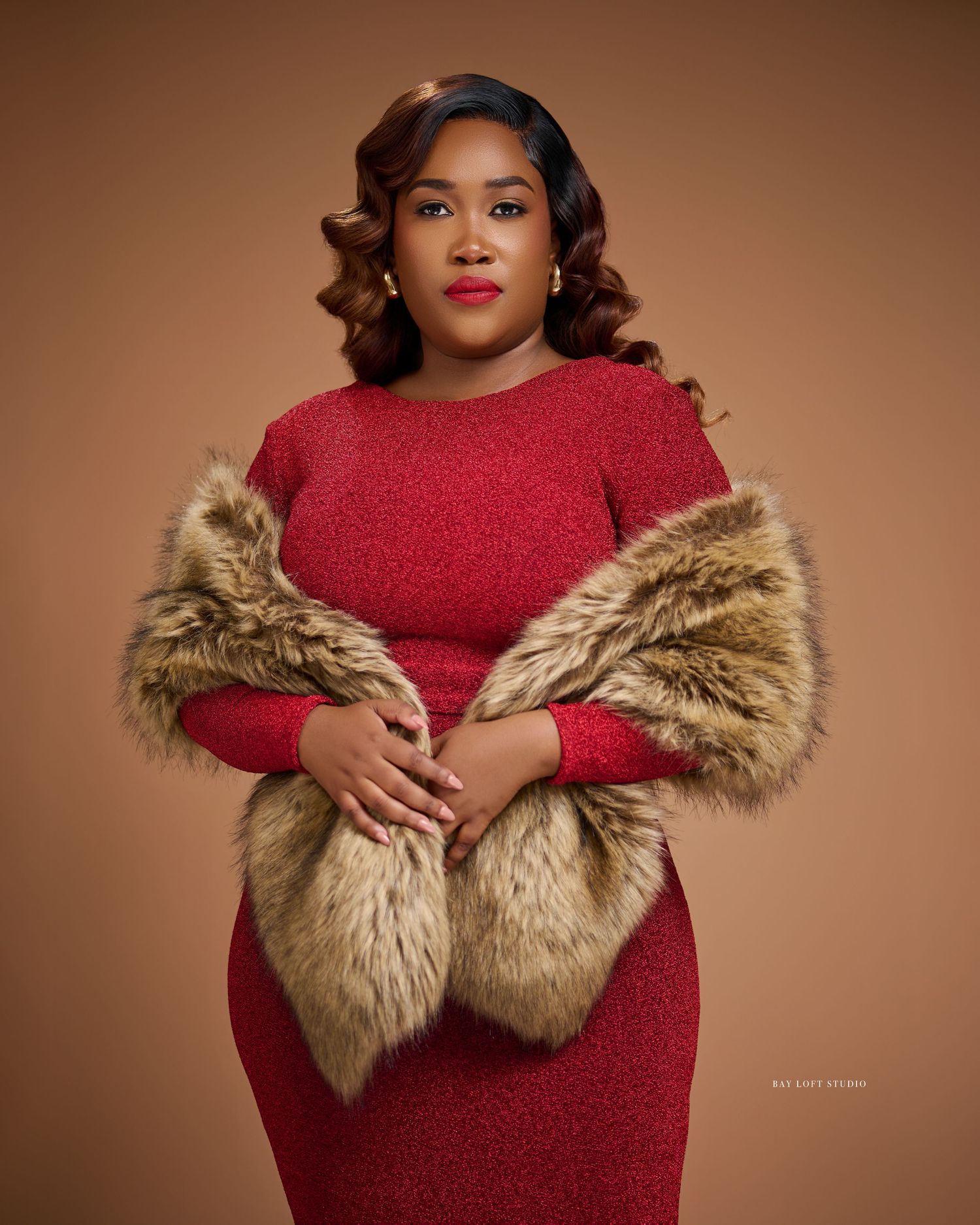 A glamorous portrait in a red sparkly dress and fur stole against a brown backdrop.