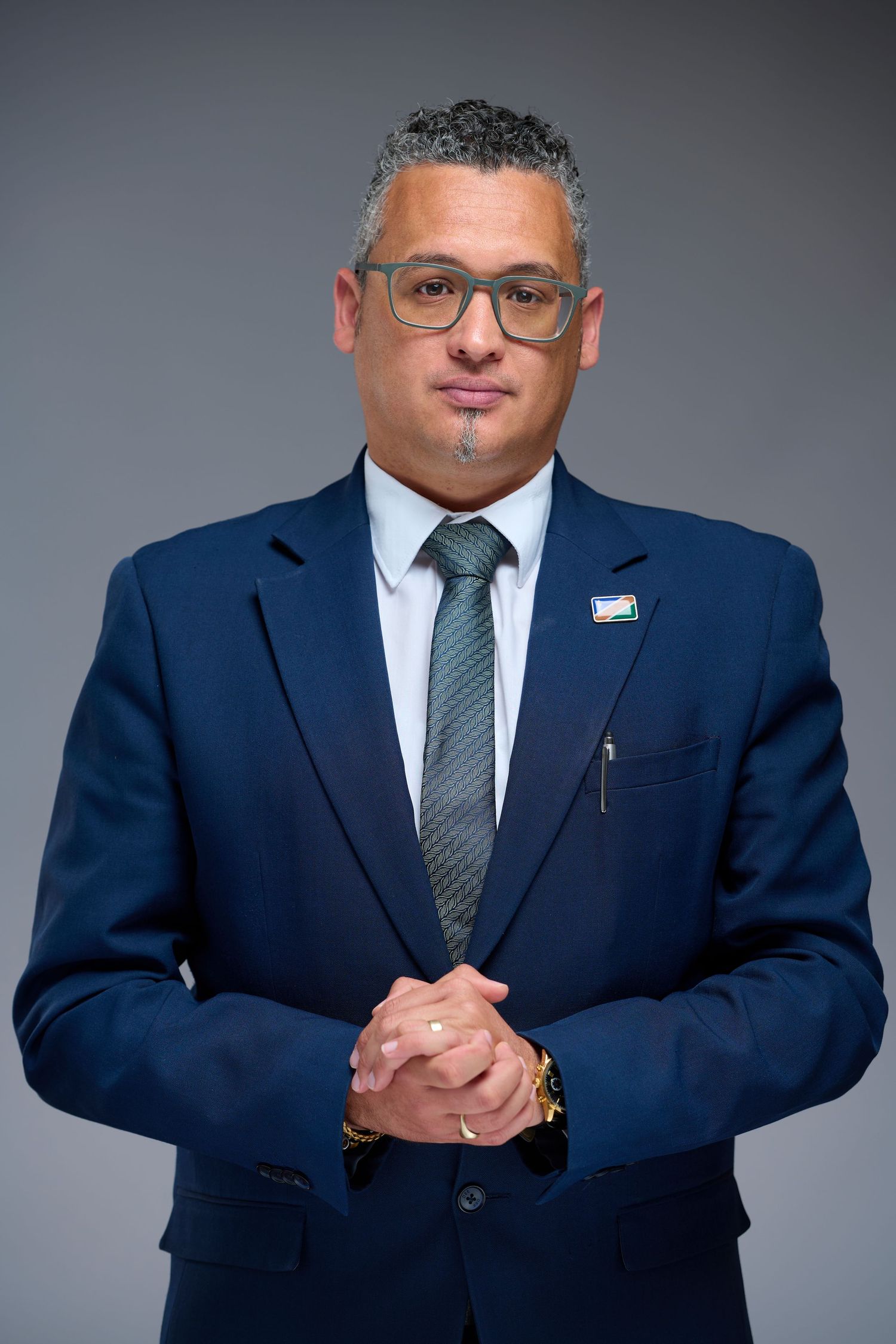 Professional portrait series showing person in navy suit and gray tie against neutral background in various poses.