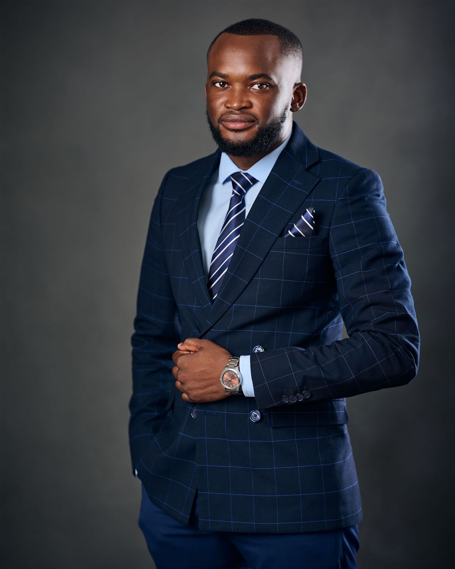 Professional man in navy blue plaid suit with striped tie posing confidently for a formal business portrait photo.