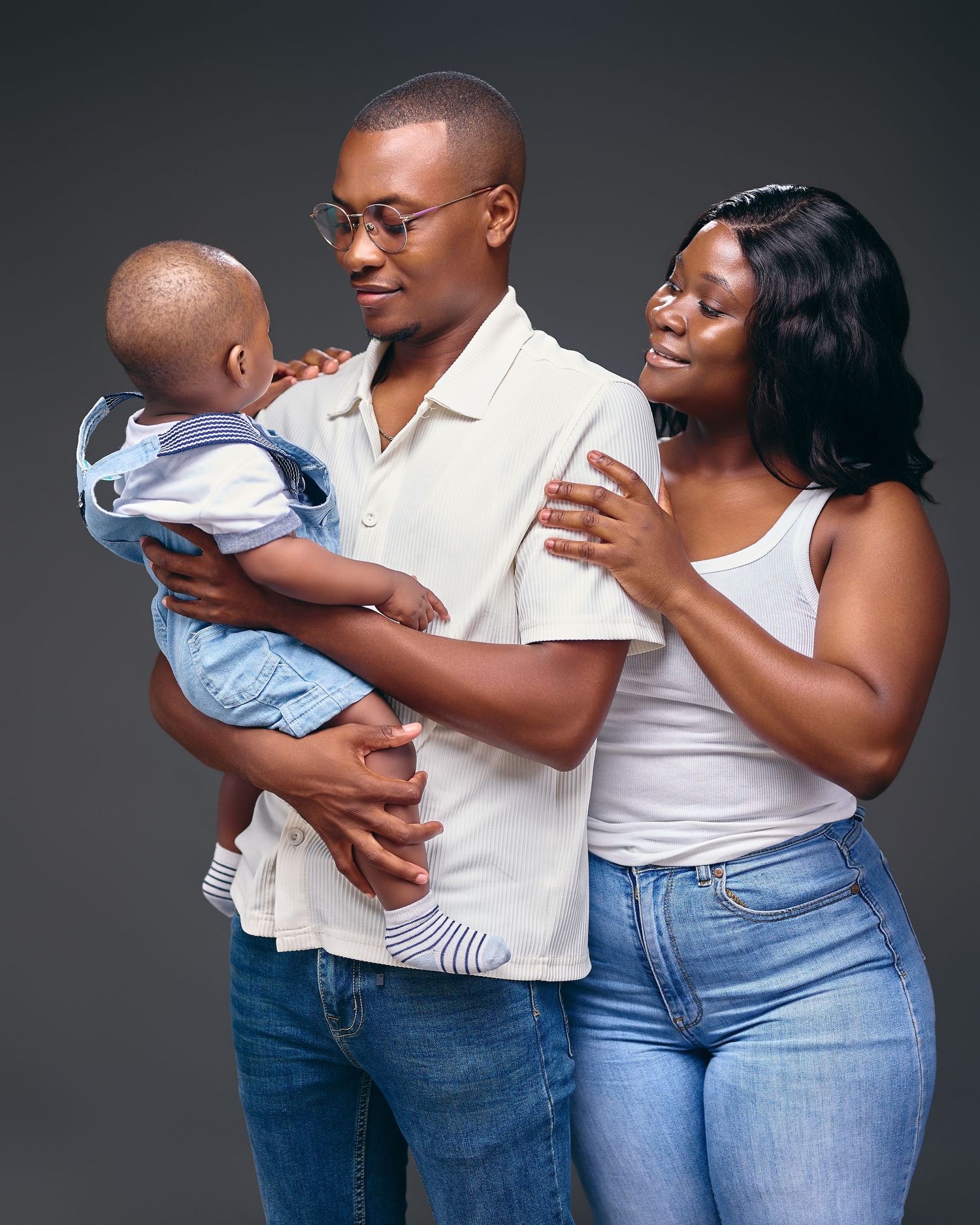 A family in coordinated blue jeans and white tops poses together for a series of intimate portraits.