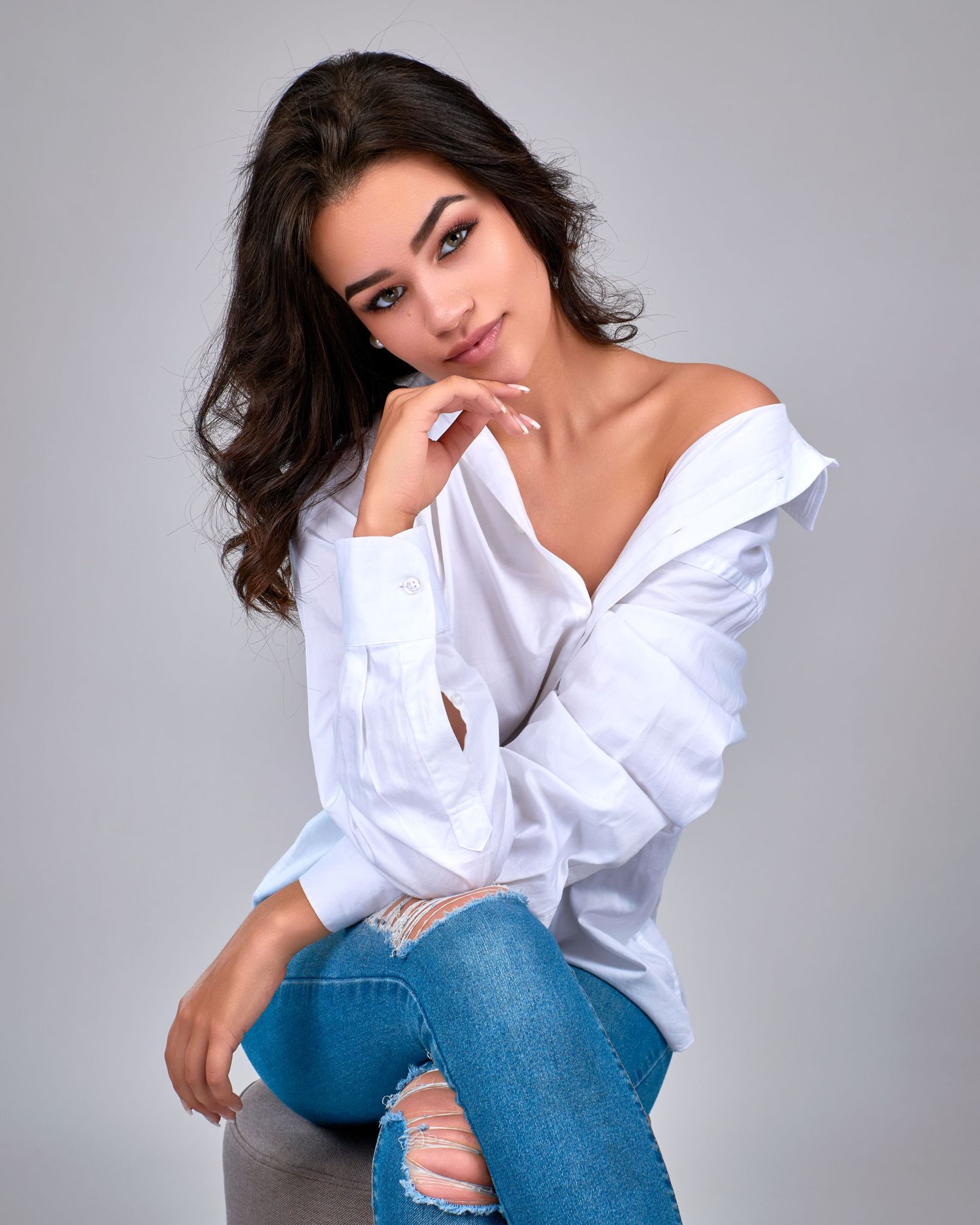 A series of fashion portraits showing a model in a white button-down shirt and blue jeans against a gray background.