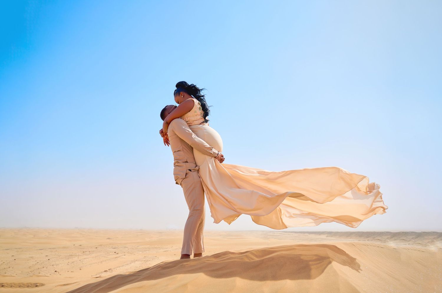 A flowing peach-colored fabric billows gracefully against a bright blue sky and desert landscape.