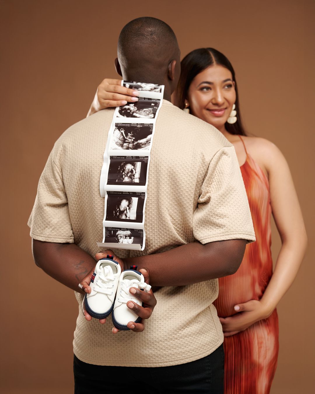 A pregnancy announcement photo series showing ultrasound images and baby shoes against a brown studio backdrop.
