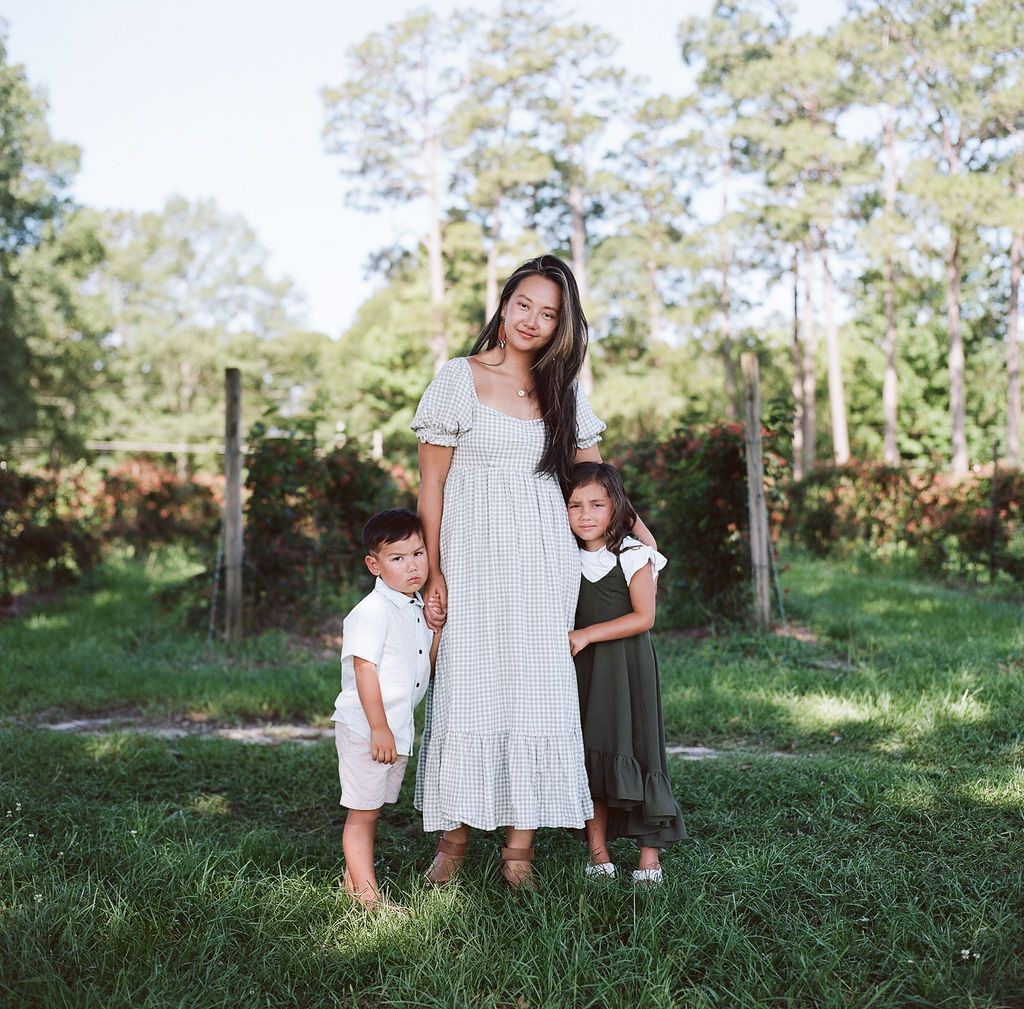 A group in white outfits stands together on grassy terrain during an outdoor photo session in natural lighting.